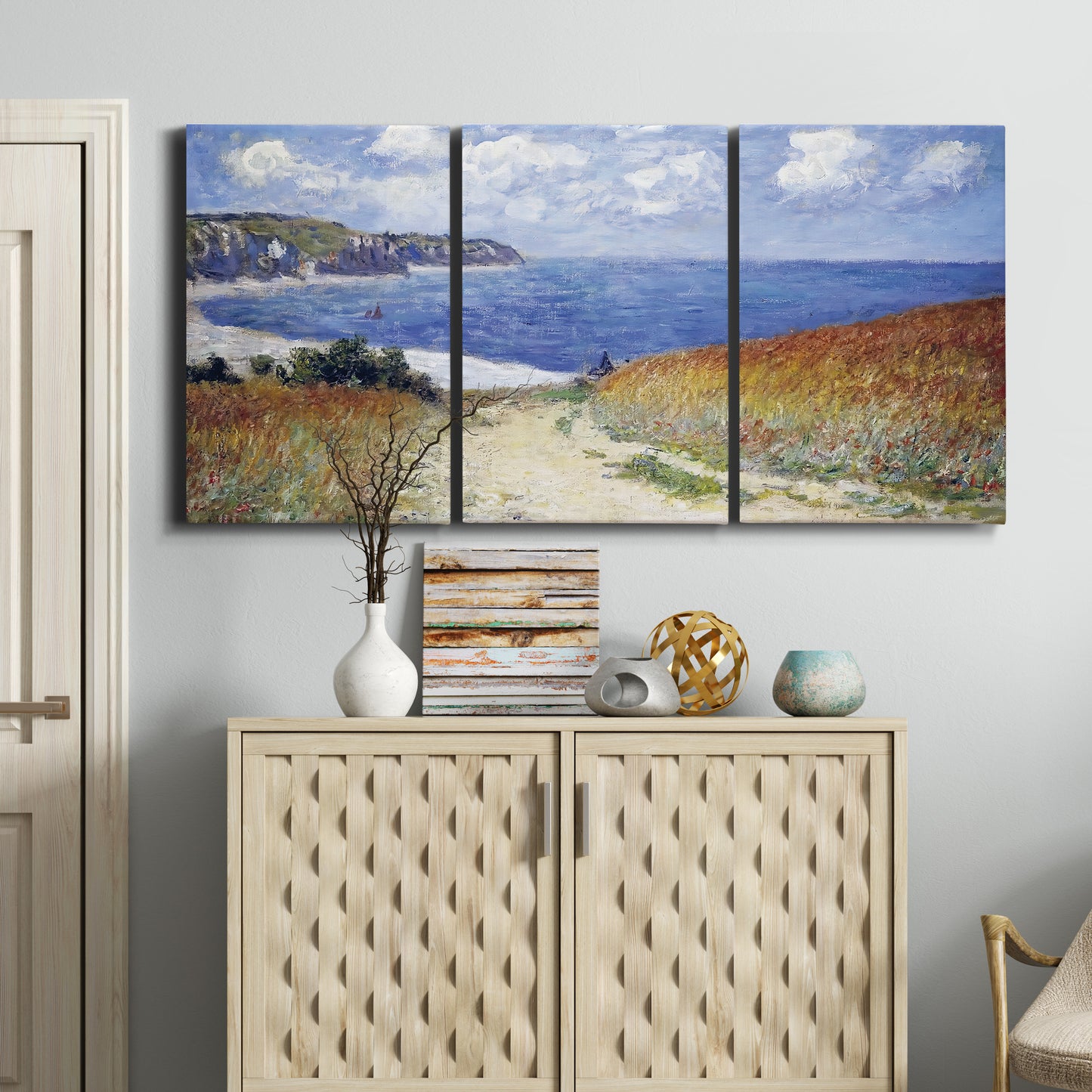 Three-panel canvas wall art featuring coastal path leading to sea, displayed above a cabinet in an entryway.