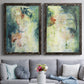 Set of two black barnwood framed canvas prints depicting paired nature-inspired mixed-media abstracts with vertical organic marks, pale light passages, and weathered surfaces above a sofa in a contemporary living room.