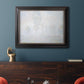 Impressionist atmospheric landscape in morning haze by Claude Monet in an ornate black frame with gilded inner detail displayed in a dark-toned interior setting.