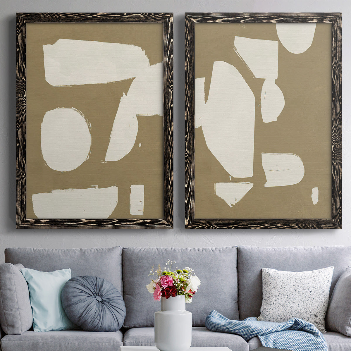 Set of two black barnwood framed canvas prints depicting paired bold minimalist shape abstracts with flat blocky forms, rough painted edges, and strong negative space above a sofa in a contemporary living room.