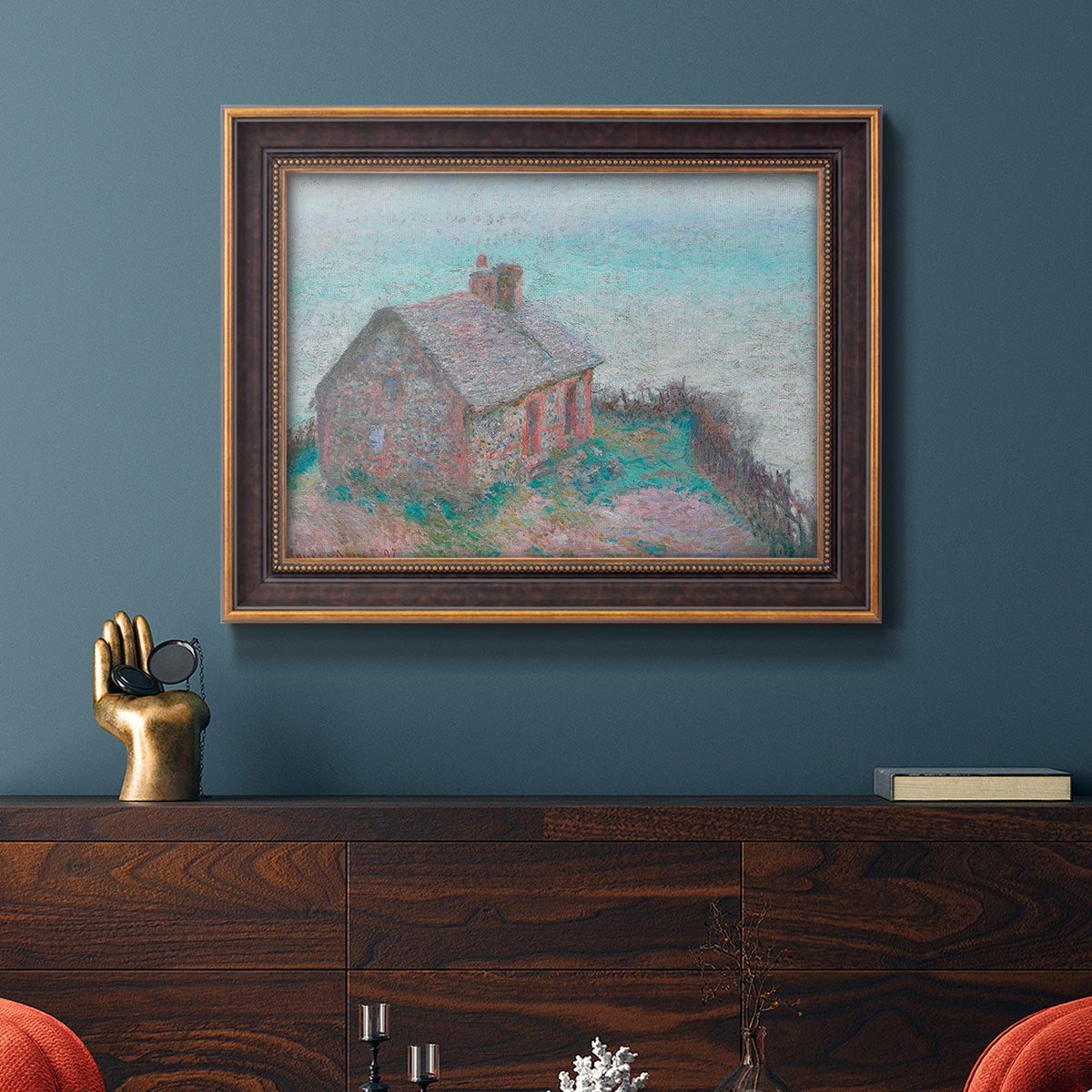 Impressionist coastal building landscape by Claude Monet in an ornate bronzed mahogany wood frame displayed in a dark-toned interior setting.