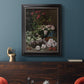 Early impressionist floral painting by Claude Monet in an ornate black frame with gilded inner detail displayed in a dark-toned interior setting.