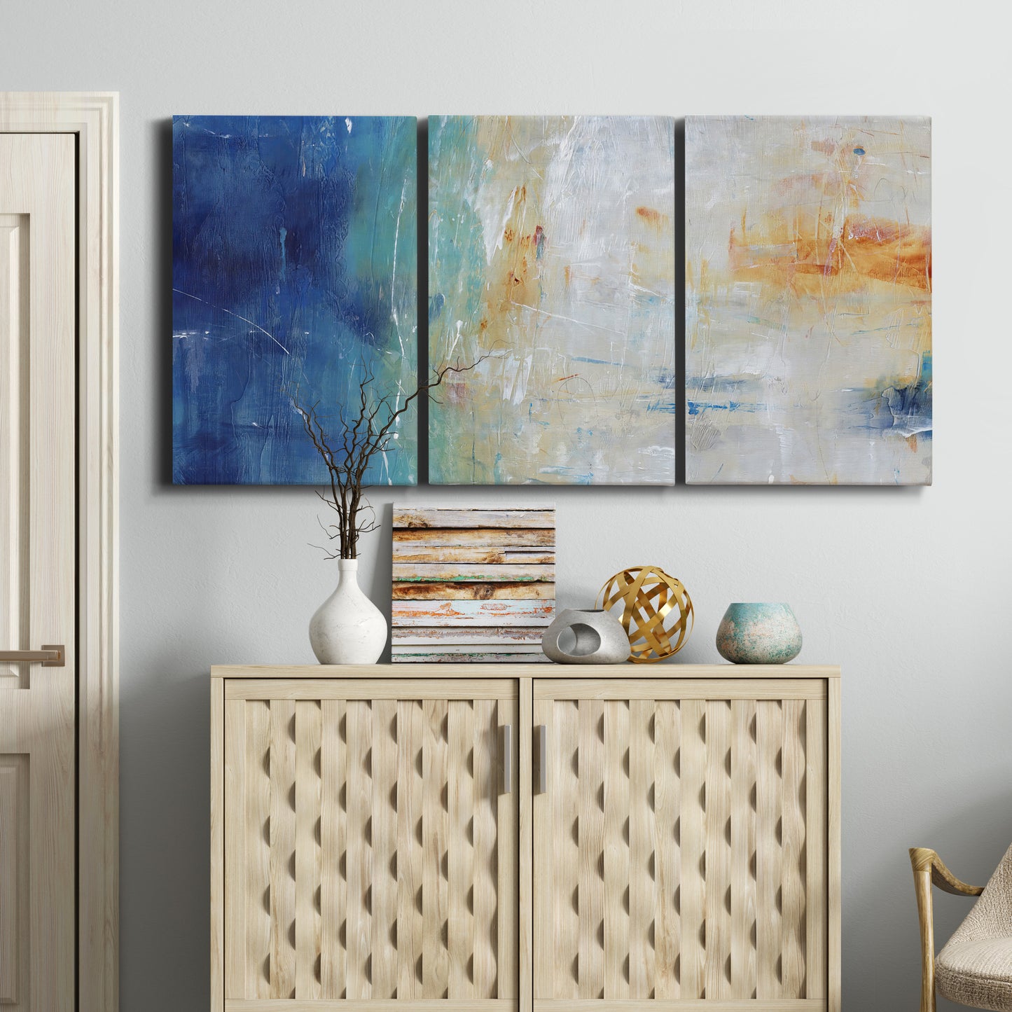 Three-panel canvas wall art featuring deep blue abstract grotto tones, displayed above a cabinet in an entryway.