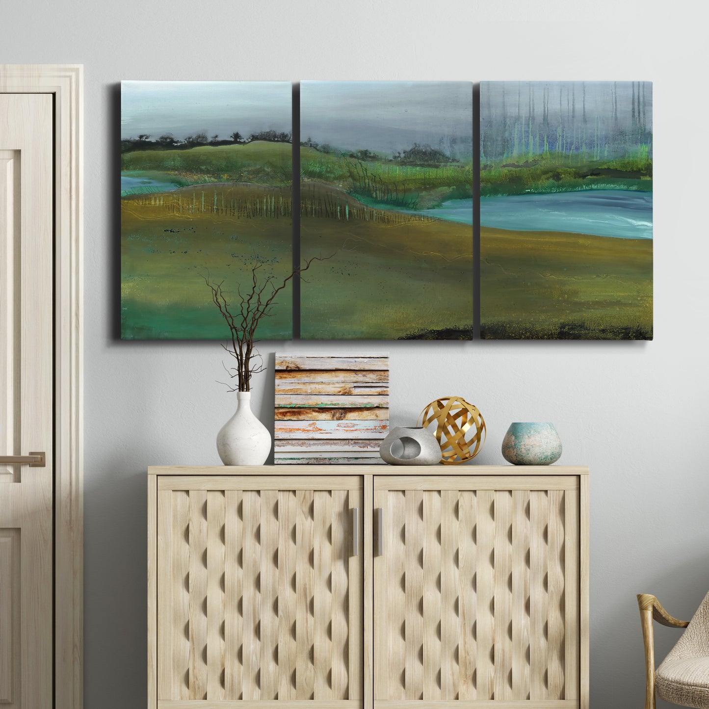 Three-panel canvas wall art featuring quiet contemplative landscape scene, displayed above a cabinet in an entryway.