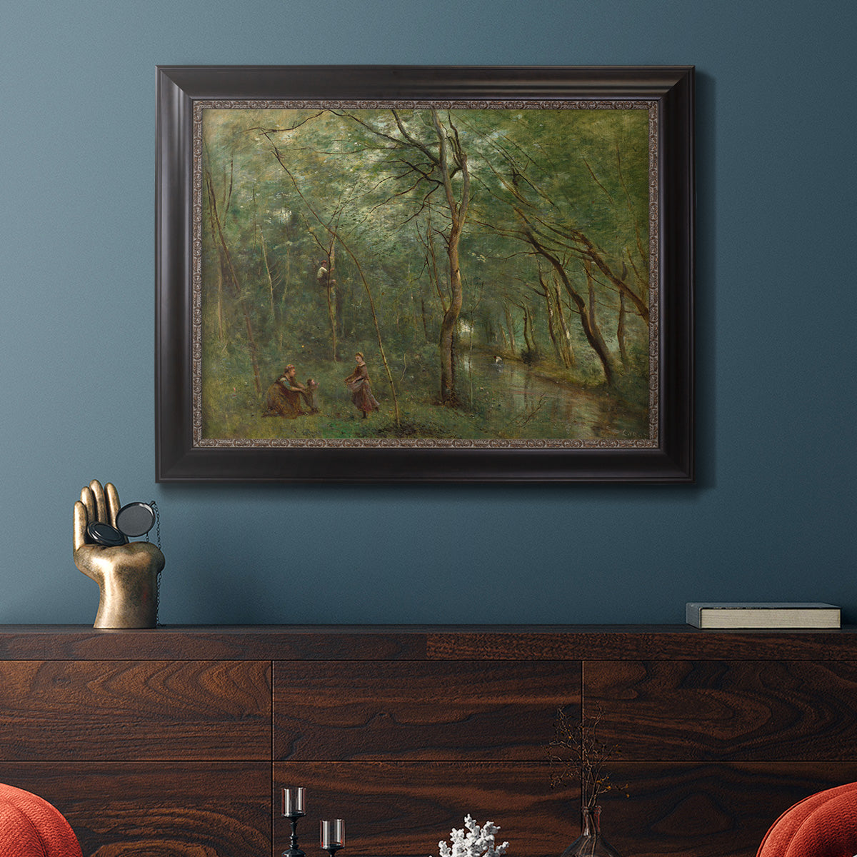 Traditional rural landscape scene with figures by Jean-Baptiste-Camille Corot in an ornate black frame with gilded inner detail displayed in a dark-toned interior setting.