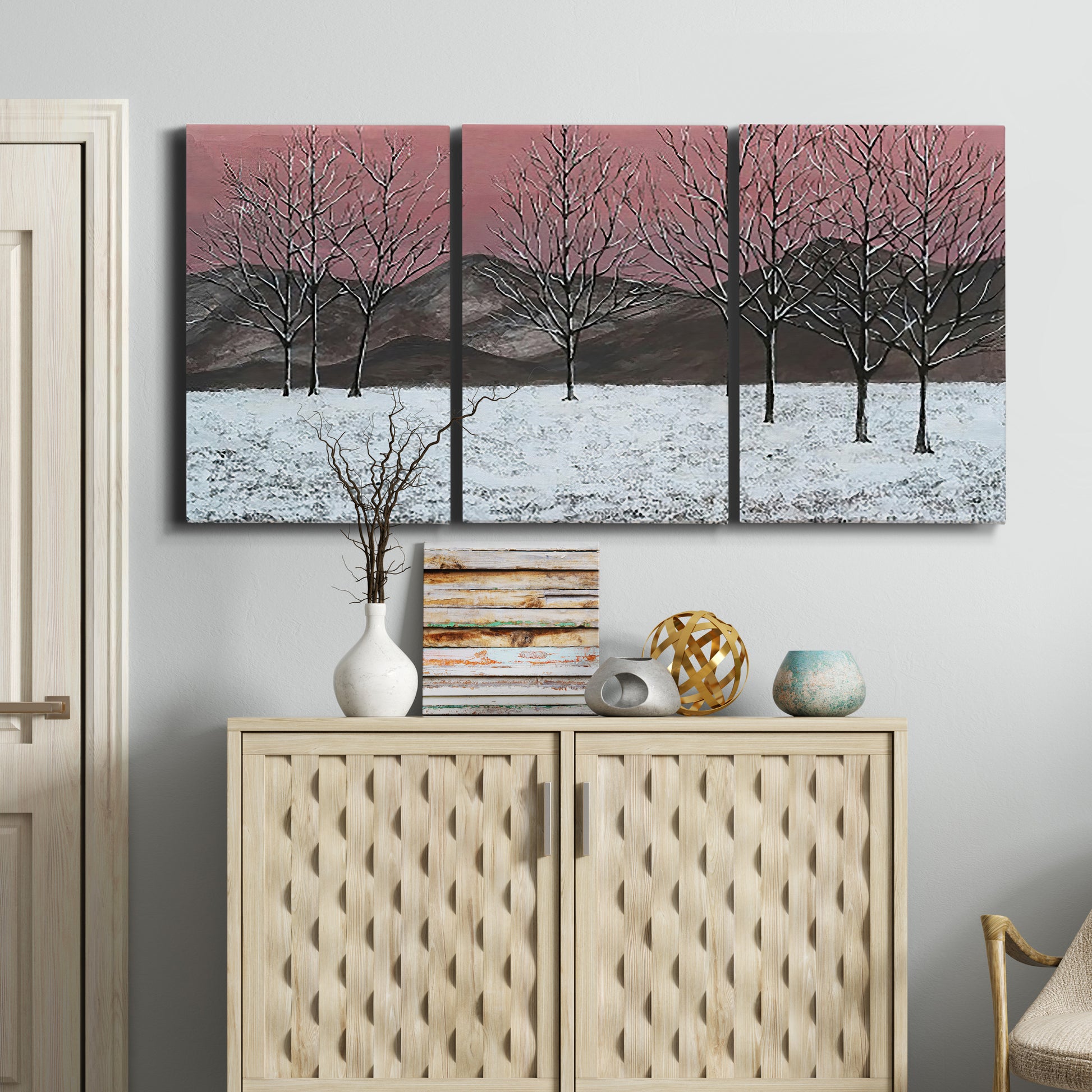 Three-panel canvas wall art featuring winter sunset snowfall landscape, displayed above a cabinet in an entryway.