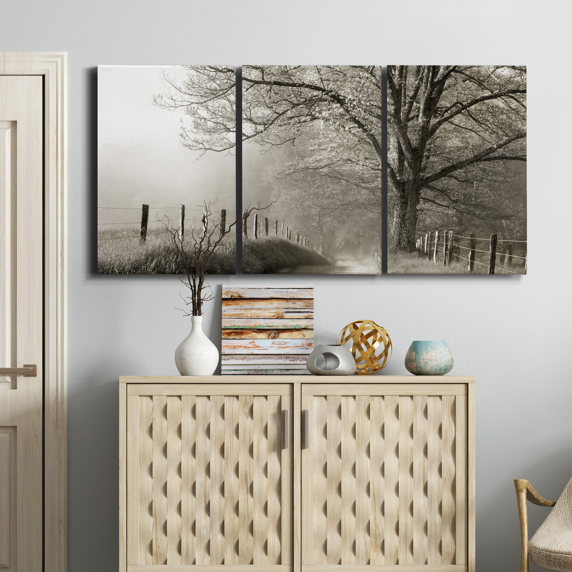 Three-panel canvas wall art featuring fenced rural path through countryside, displayed above a cabinet in an entryway.