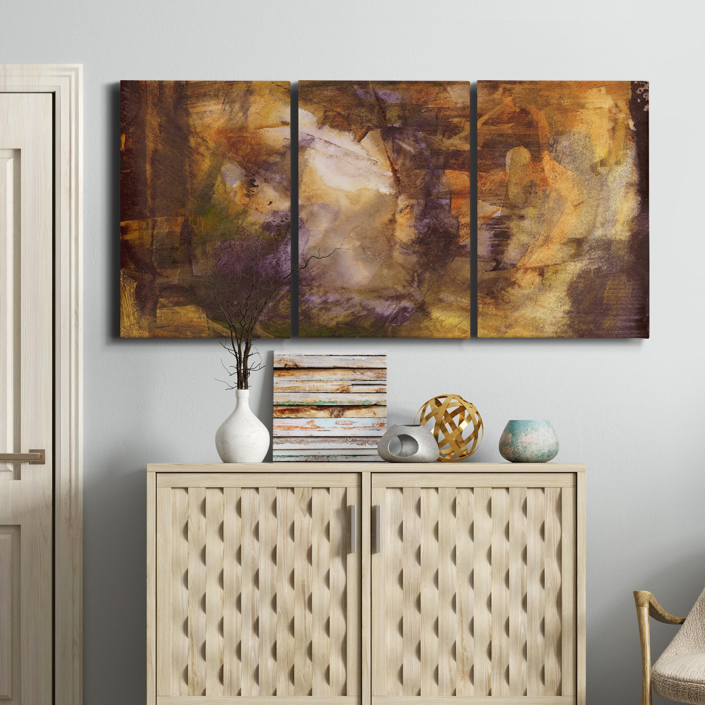 Three-panel canvas wall art featuring abstract architectural landscape, displayed above a cabinet in an entryway.