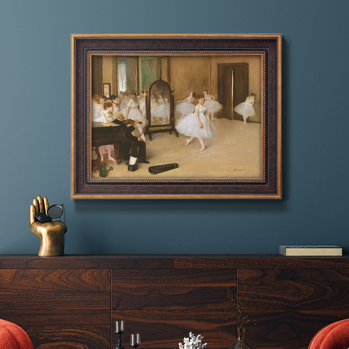 Impressionist dance class interior scene by Edgar Degas in an ornate bronzed mahogany wood frame displayed in a dark-toned interior setting.