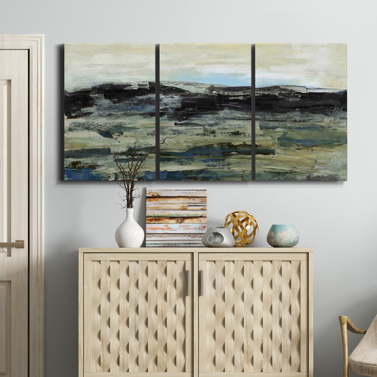 Three-panel canvas wall art featuring muted abstract landscape study, displayed above a cabinet in an entryway.