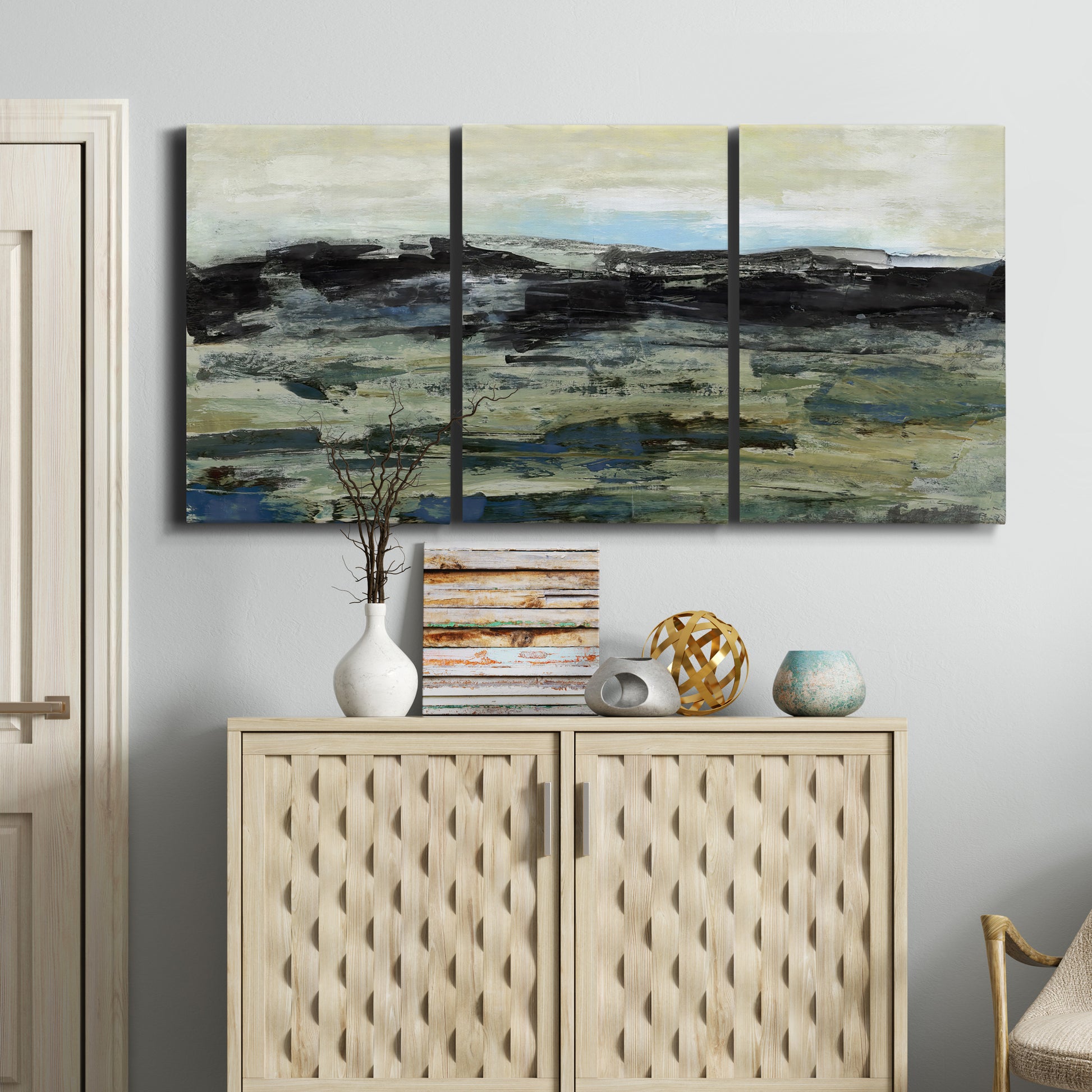 Three-panel canvas wall art featuring muted abstract landscape study, displayed above a cabinet in an entryway.