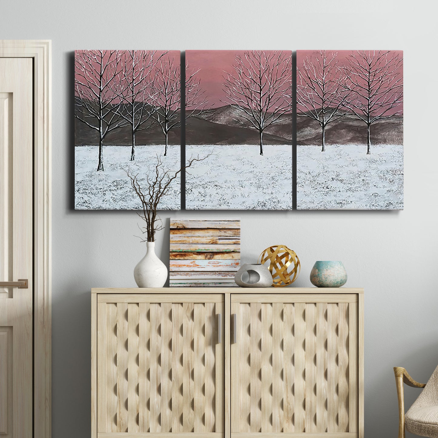Three-panel canvas wall art featuring winter sunset snowfall landscape, displayed above a cabinet in an entryway.
