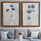 Set of two maple barnwood framed canvas prints depicting paired rustic monochrome botanical paintings with indigo blossoms, thin stems, and softly distressed gray backgrounds above a sofa in a contemporary living room.