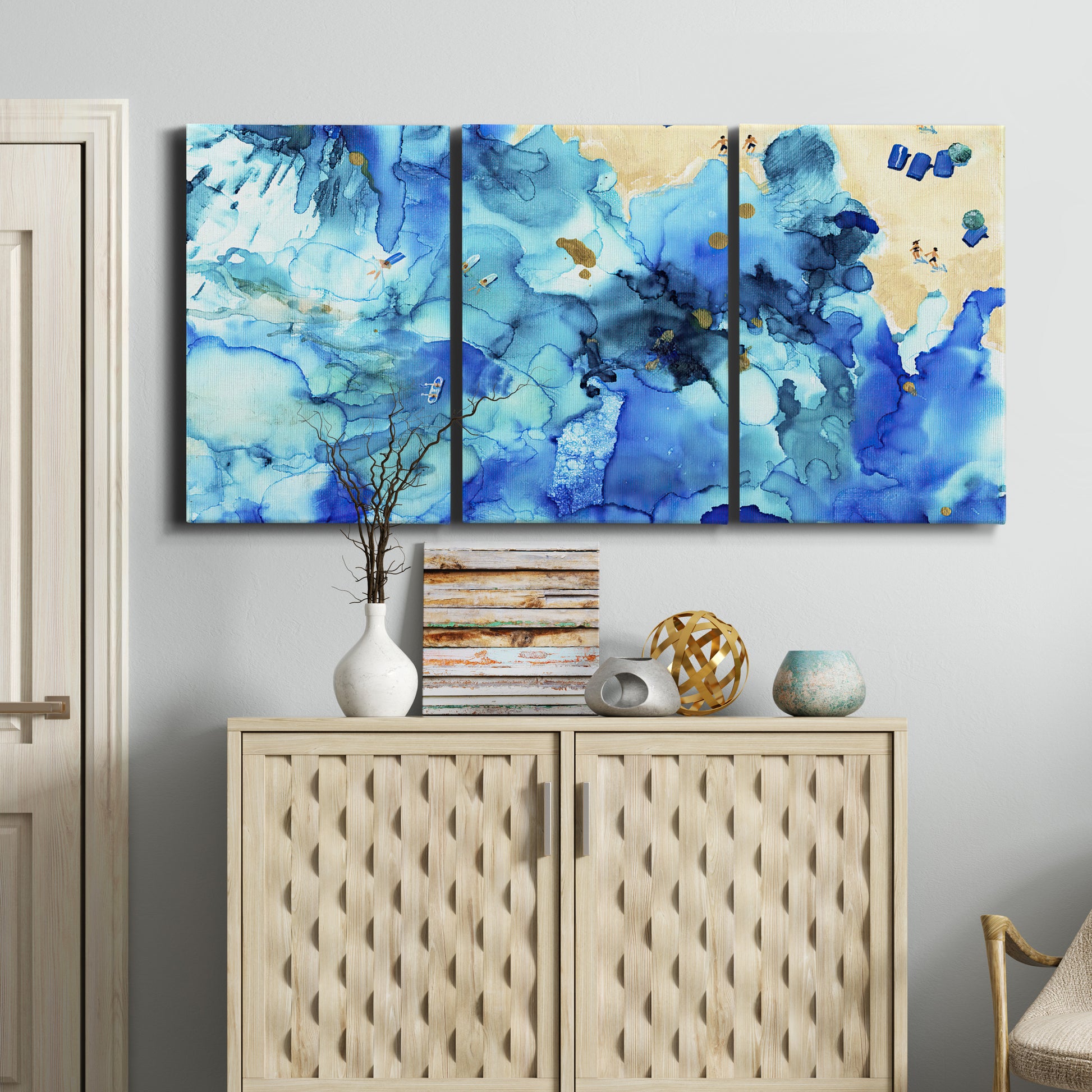 Three-panel canvas wall art featuring abstract coastal beach color fields, displayed above a cabinet in an entryway.