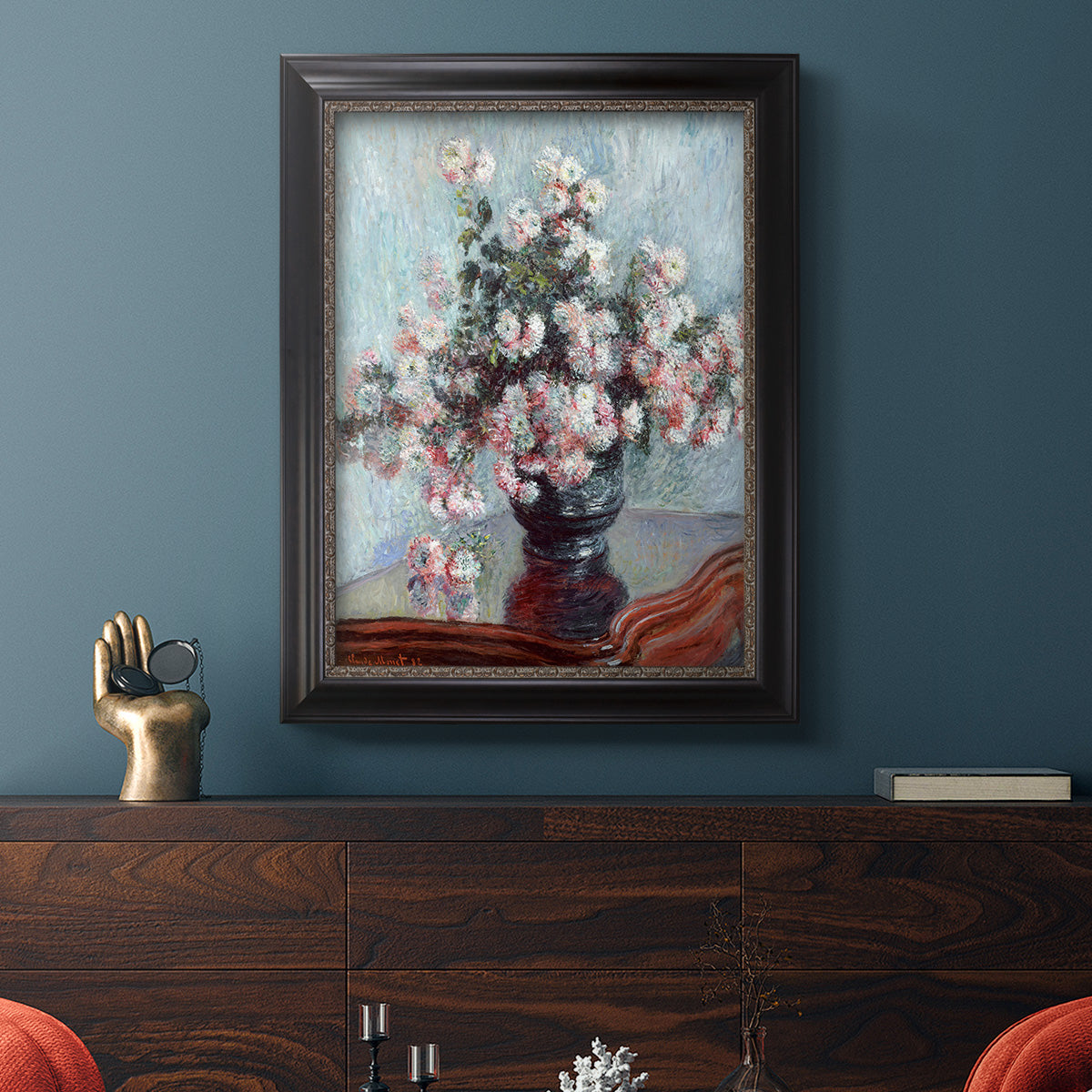 Impressionist chrysanthemum floral painting by Claude Monet in an ornate black frame with gilded inner detail displayed in a dark-toned interior setting.