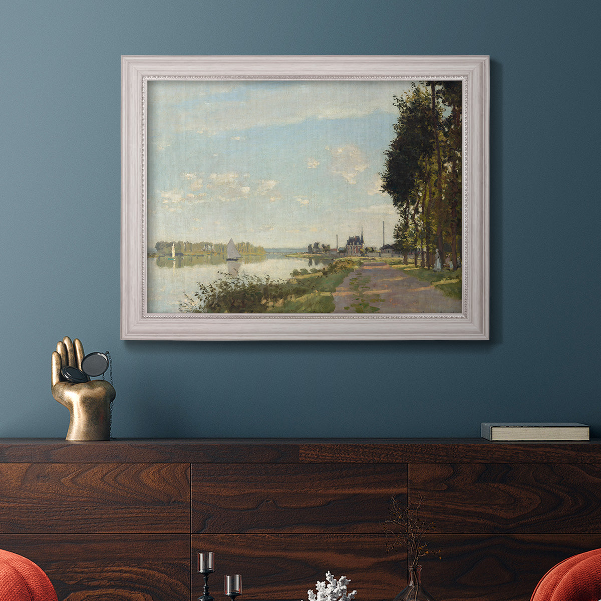 Impressionist river scene with red boats by Claude Monet in an ornate weathered white frame displayed in a dark-toned interior setting.