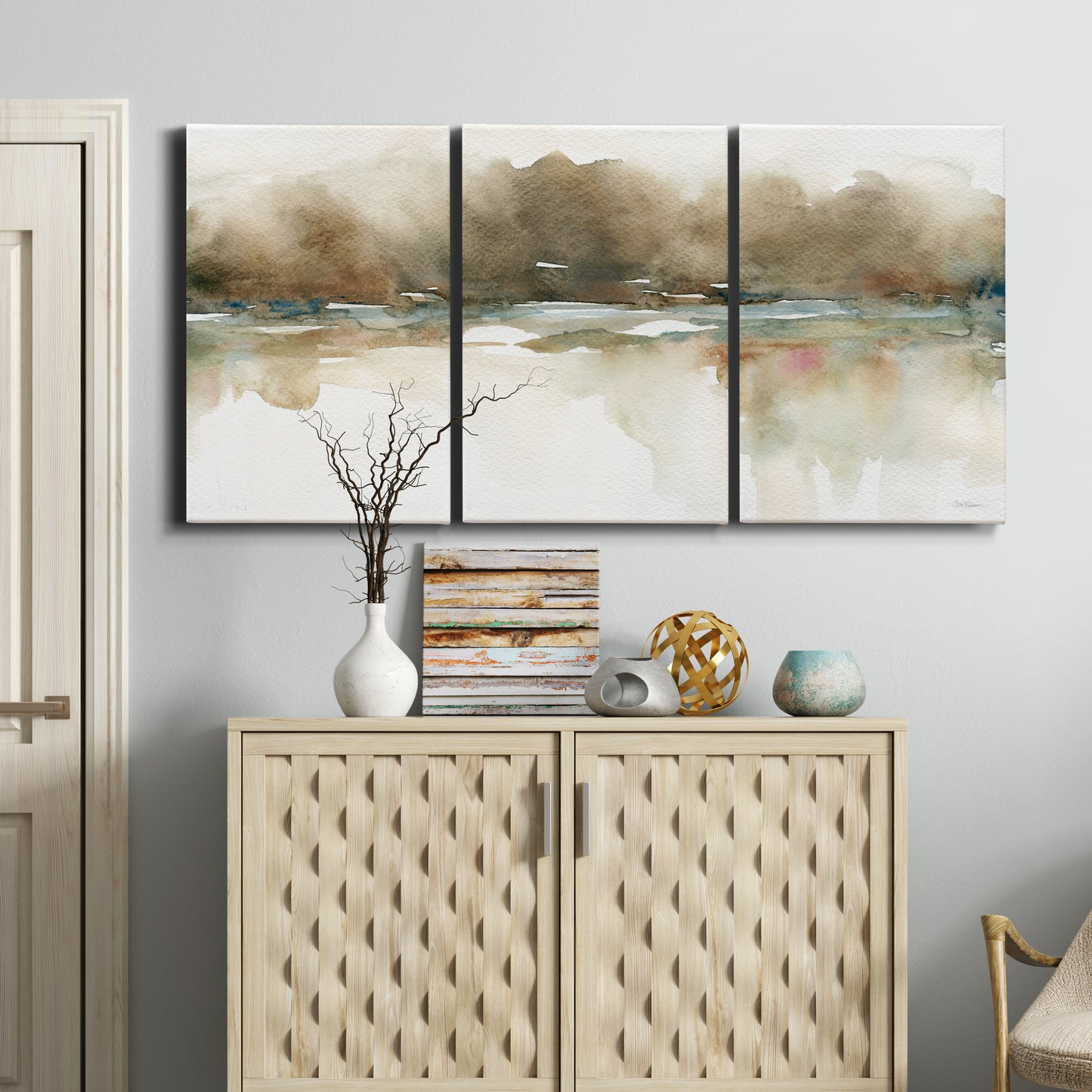 Three-panel canvas wall art featuring soft abstract mirrored reflections, displayed above a cabinet in an entryway.