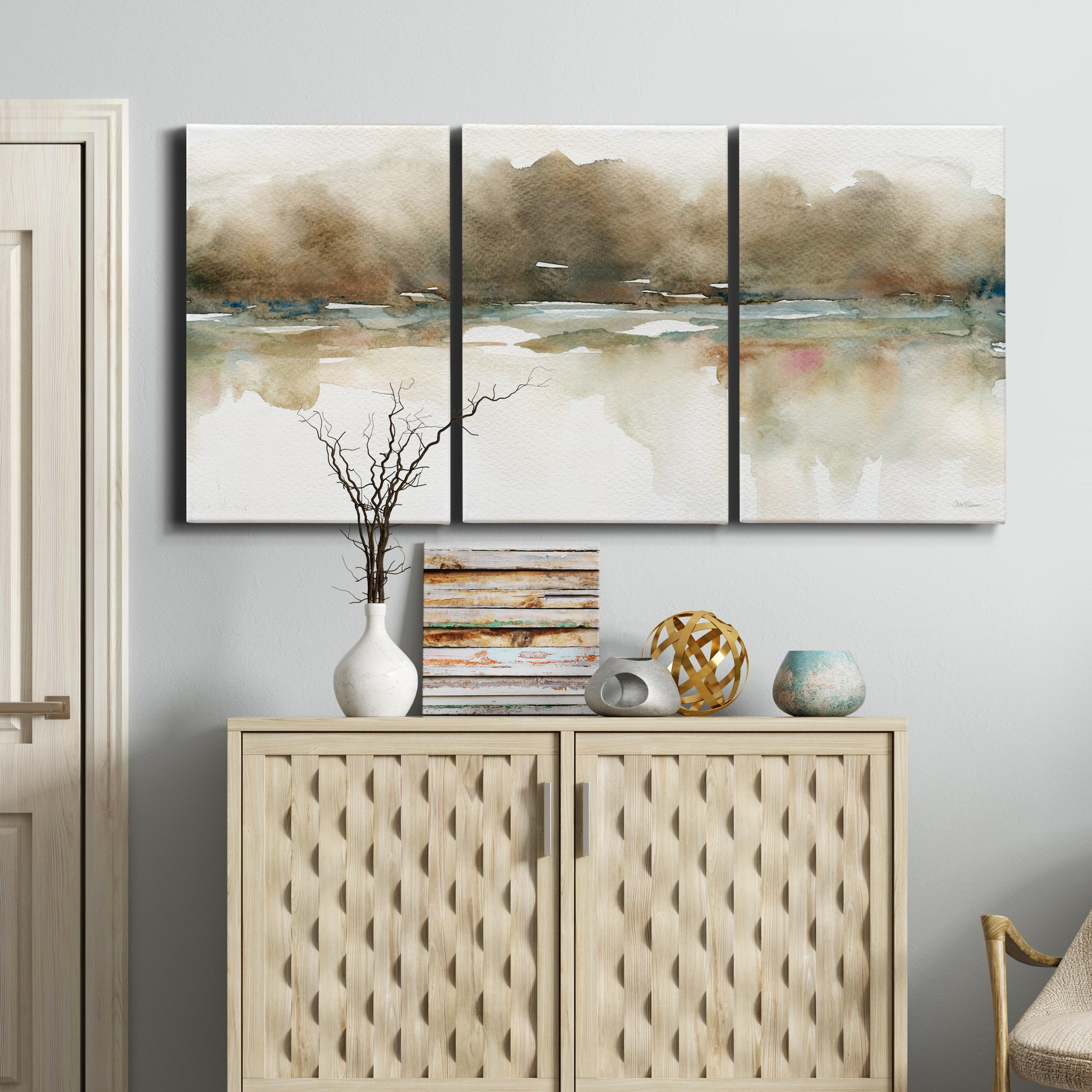 Three-panel canvas wall art featuring soft abstract mirrored reflections, displayed above a cabinet in an entryway.