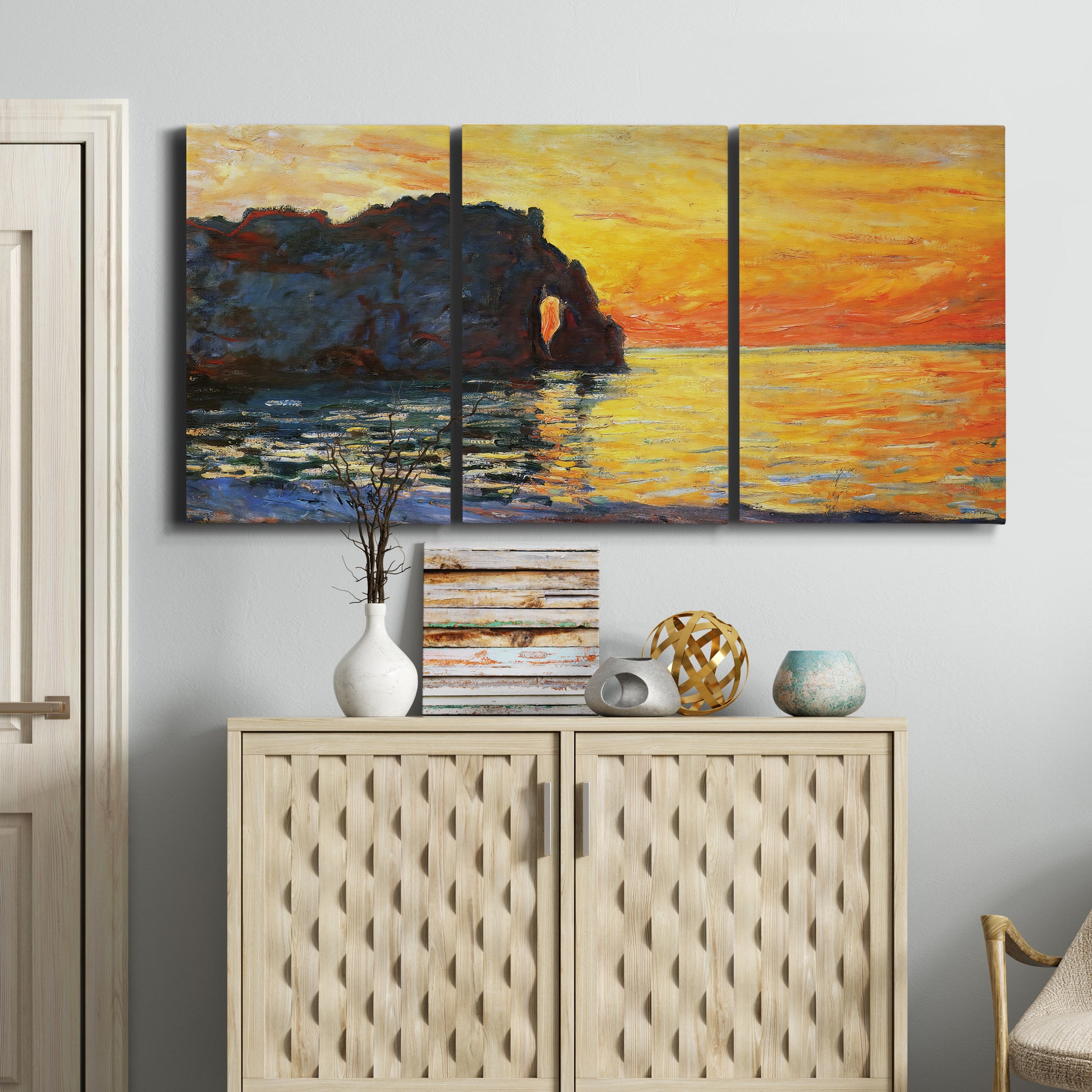 Three-panel canvas wall art featuring arched coastal cliff above sea, displayed above a cabinet in an entryway.