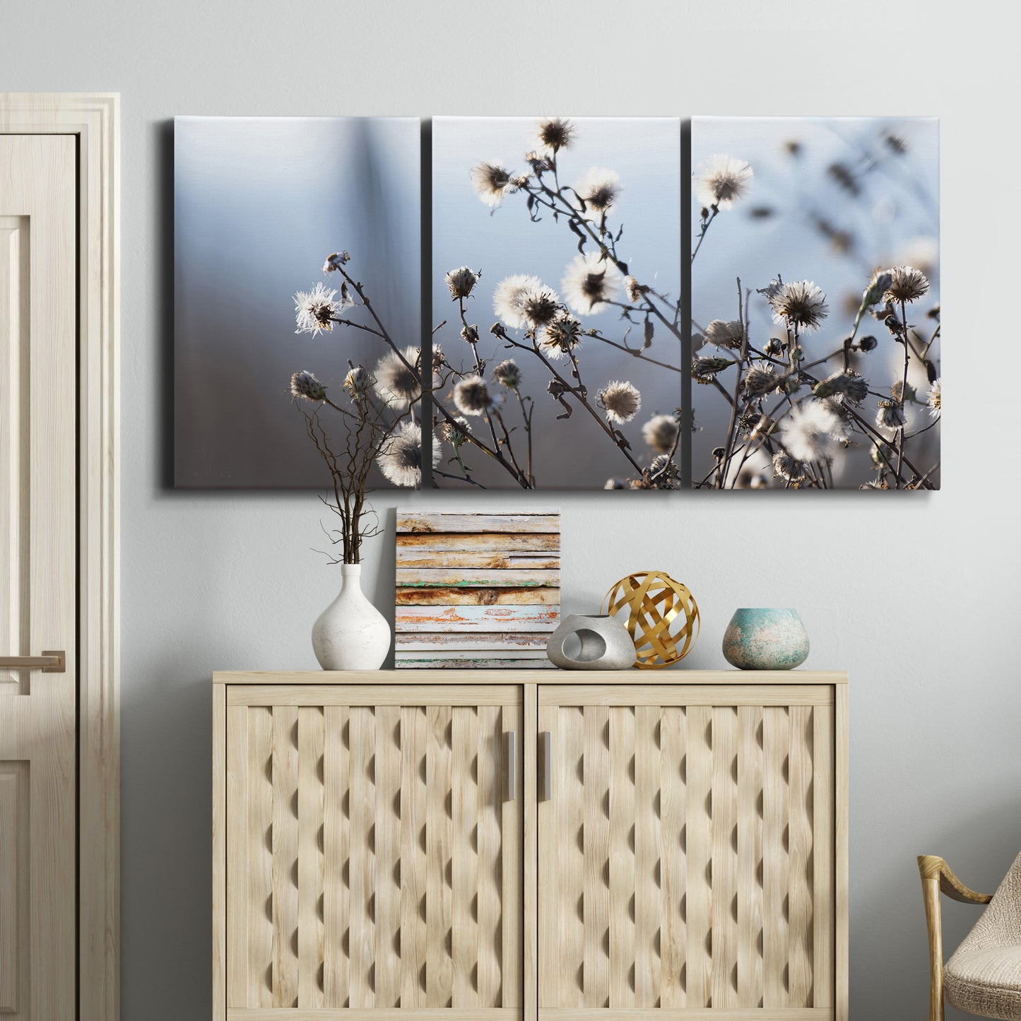 Three-panel canvas wall art featuring delicate spring blossoms on branches, displayed above a cabinet in an entryway.
