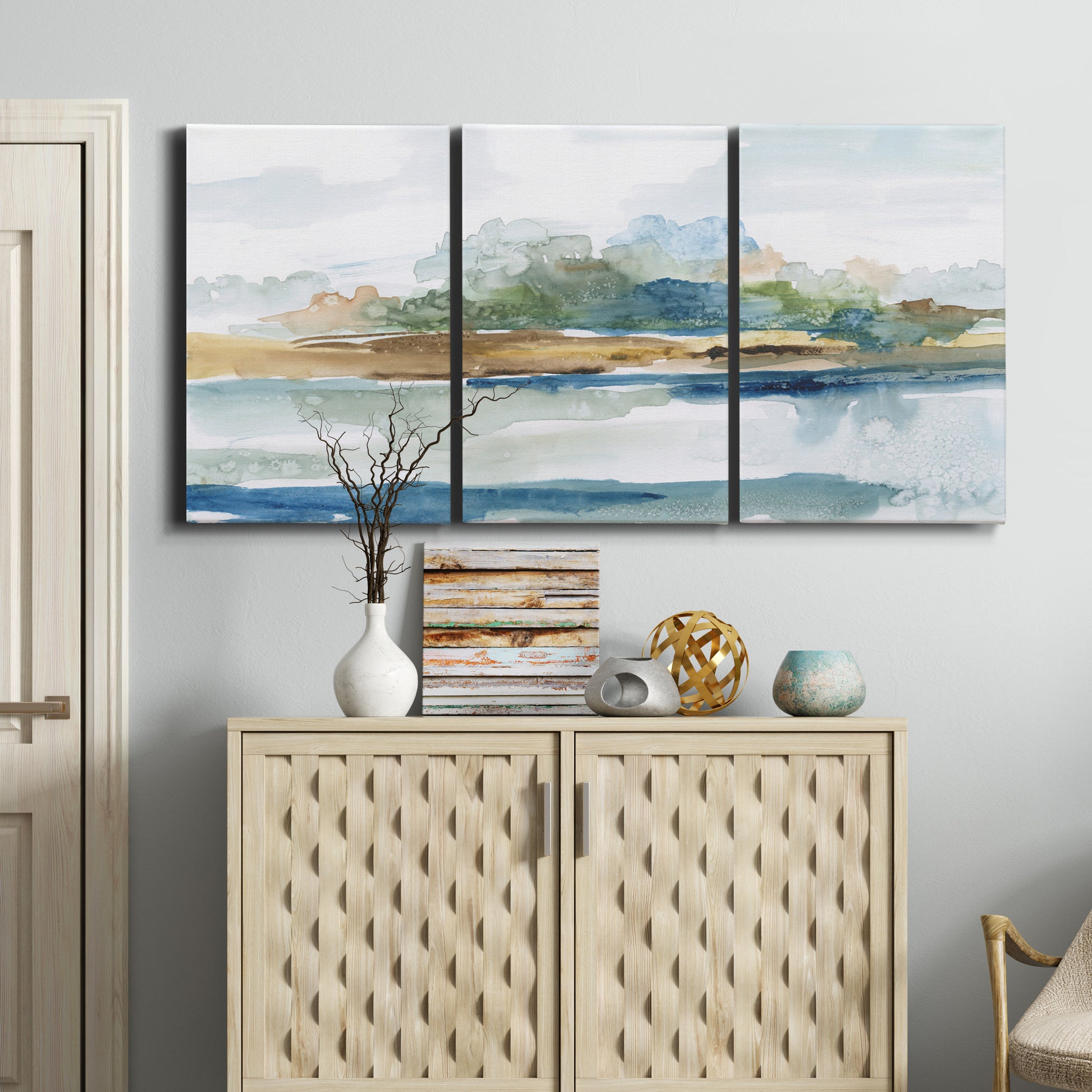 Three-panel canvas wall art featuring flowing blue abstract watercolor, displayed above a cabinet in an entryway.