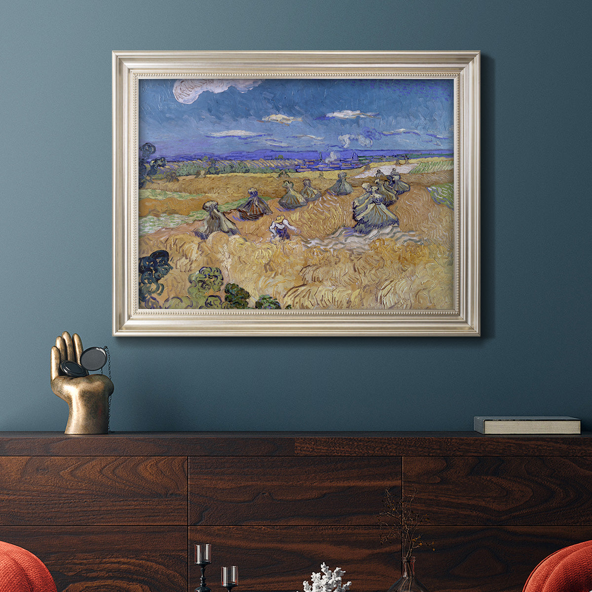 Impressionist wheat harvest scene by Vincent van Gogh in an ornate champagne frame displayed in a dark-toned interior setting.