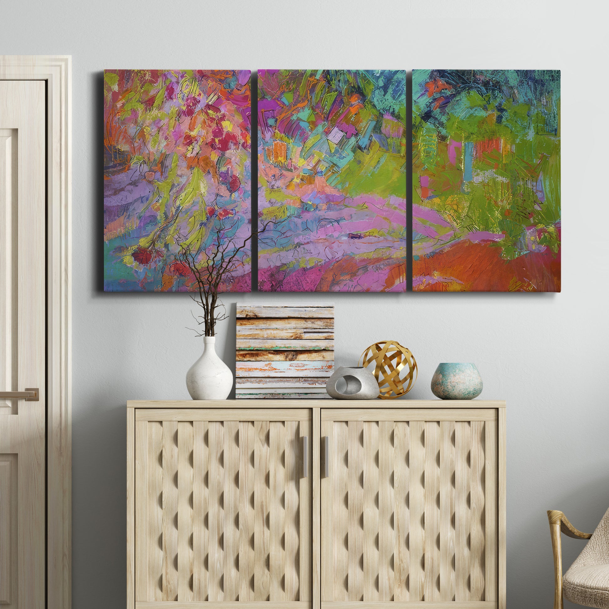Three-panel canvas wall art featuring vibrant abstract with dramatic motion, displayed above a cabinet in an entryway.