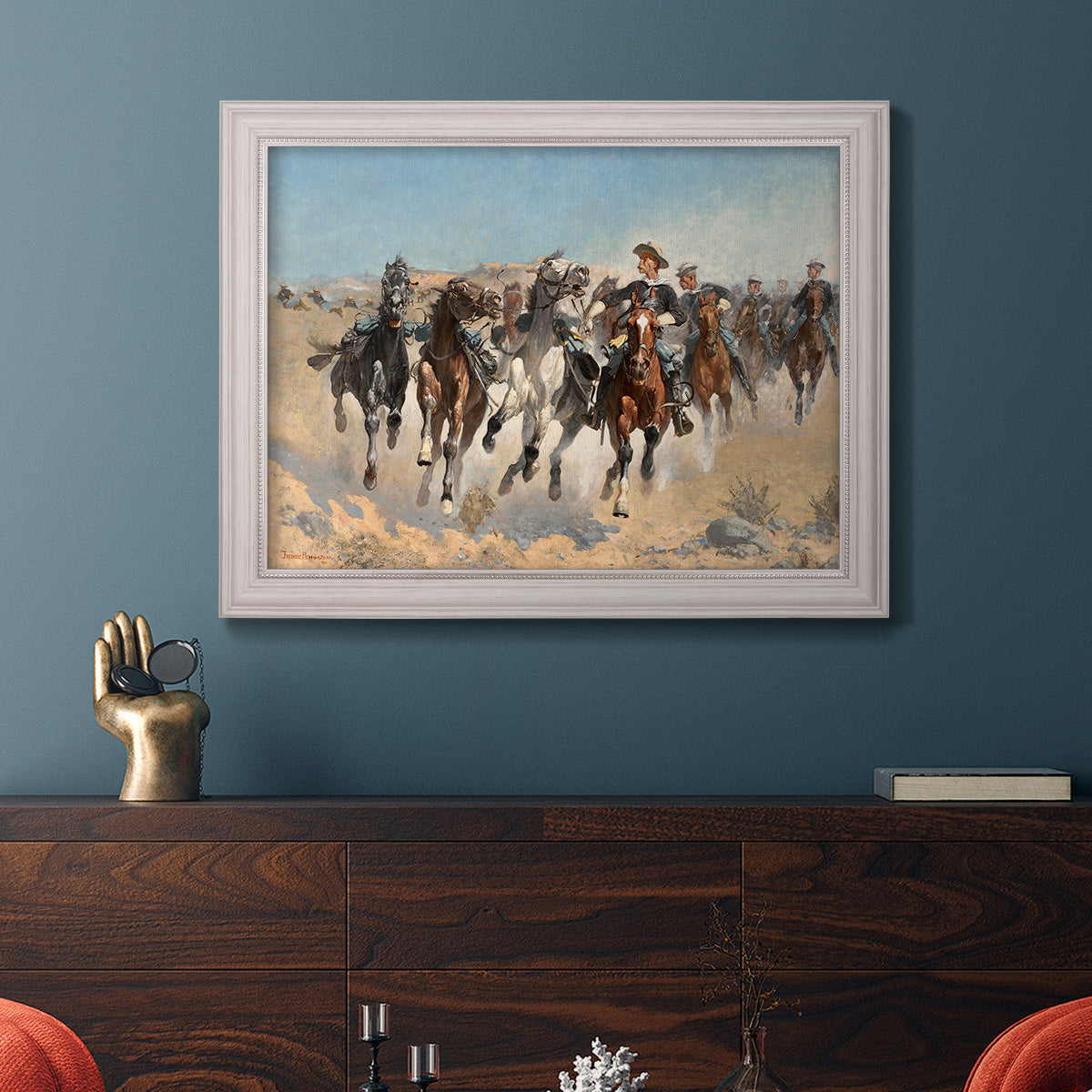 Impressionist western action scene by Frederic Remington in an ornate weathered white frame displayed in a dark-toned interior setting.