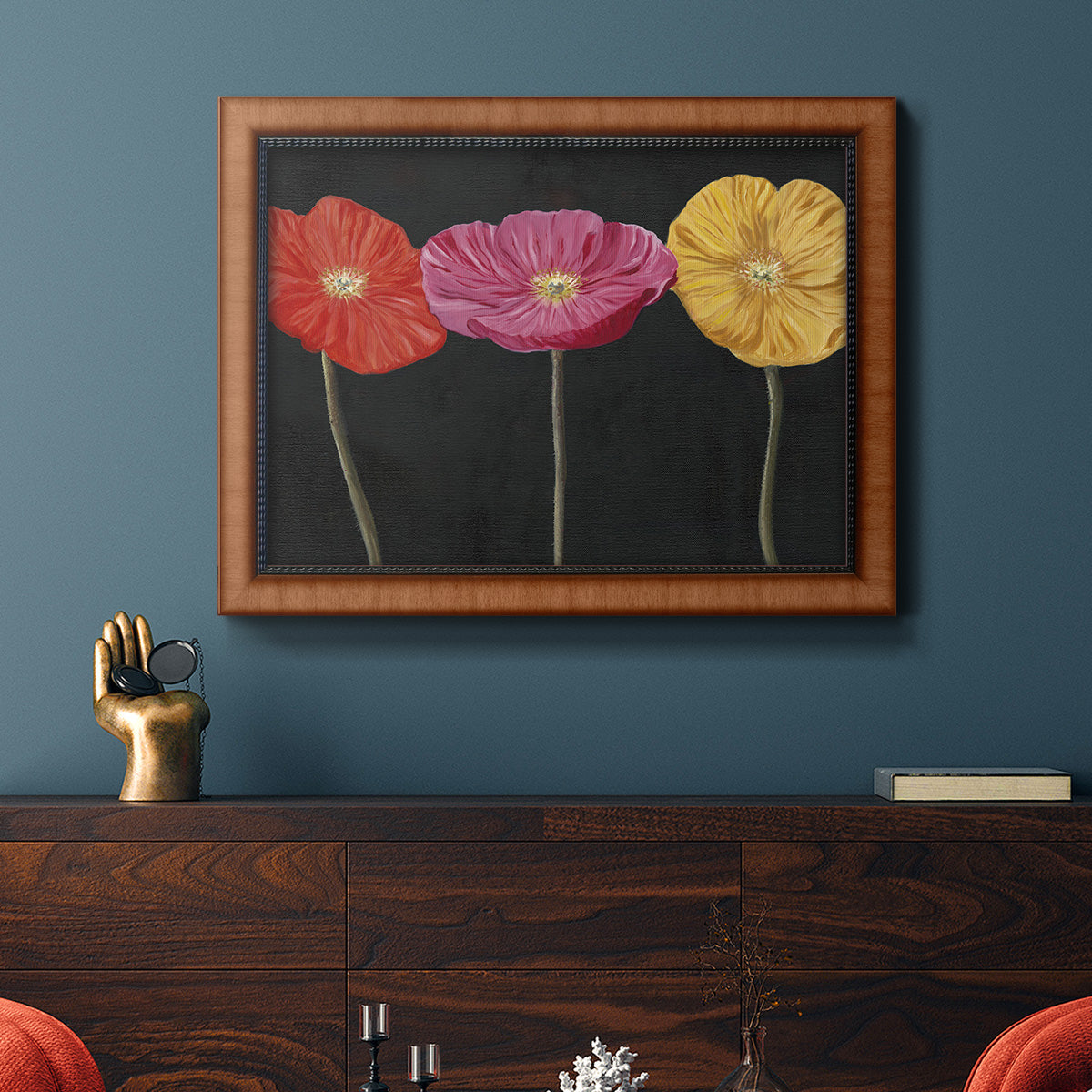 Contemporary poppy flower artwork in an ornate vintage burl wood frame displayed in a dark-toned interior setting.