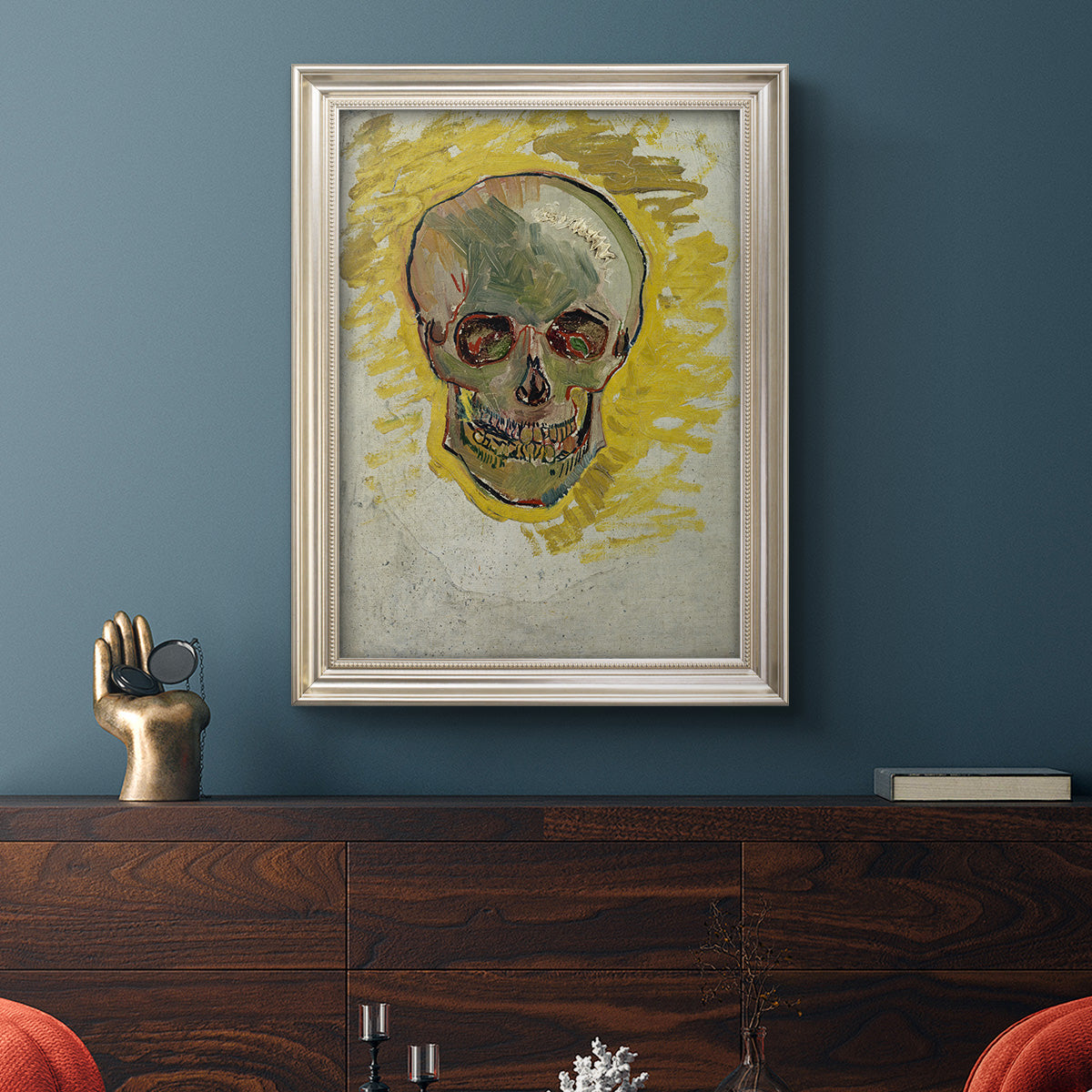 Expressive skull study painting by Vincent van Gogh in an ornate champagne frame displayed in a dark-toned interior setting.