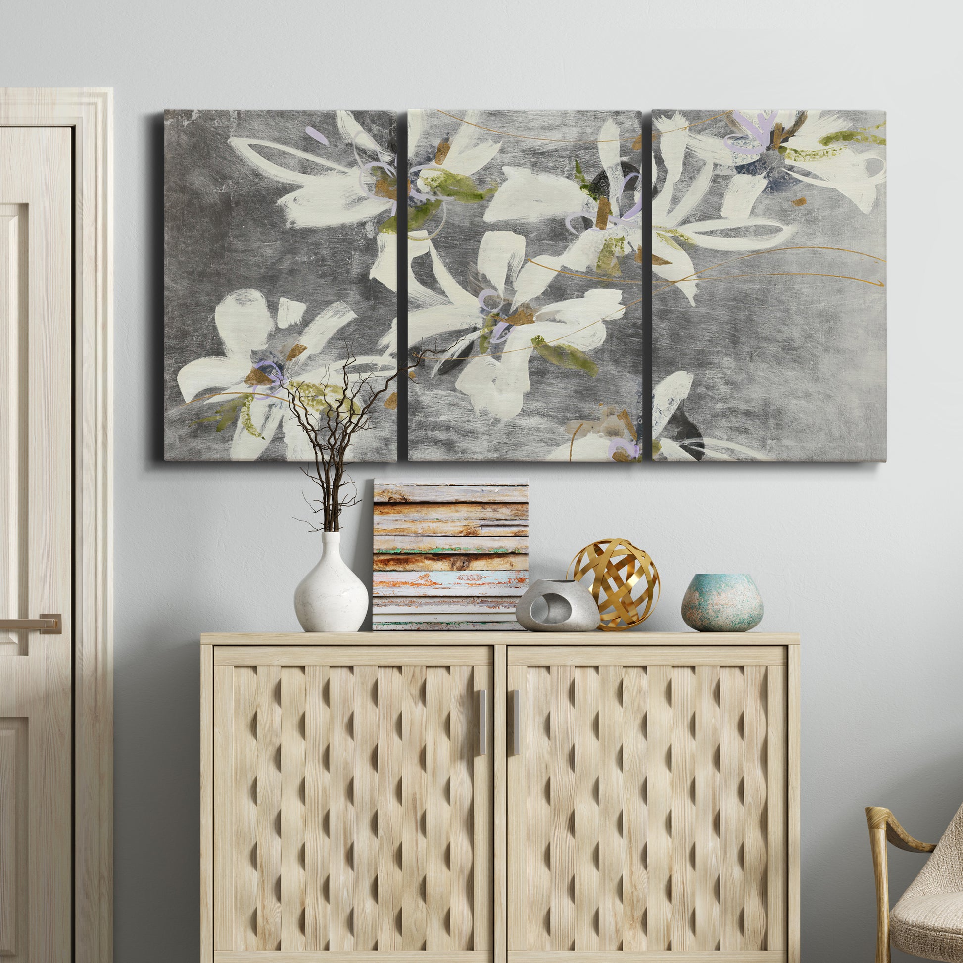 Three-panel canvas wall art featuring delicate floral symbolic arrangement, displayed above a cabinet in an entryway.