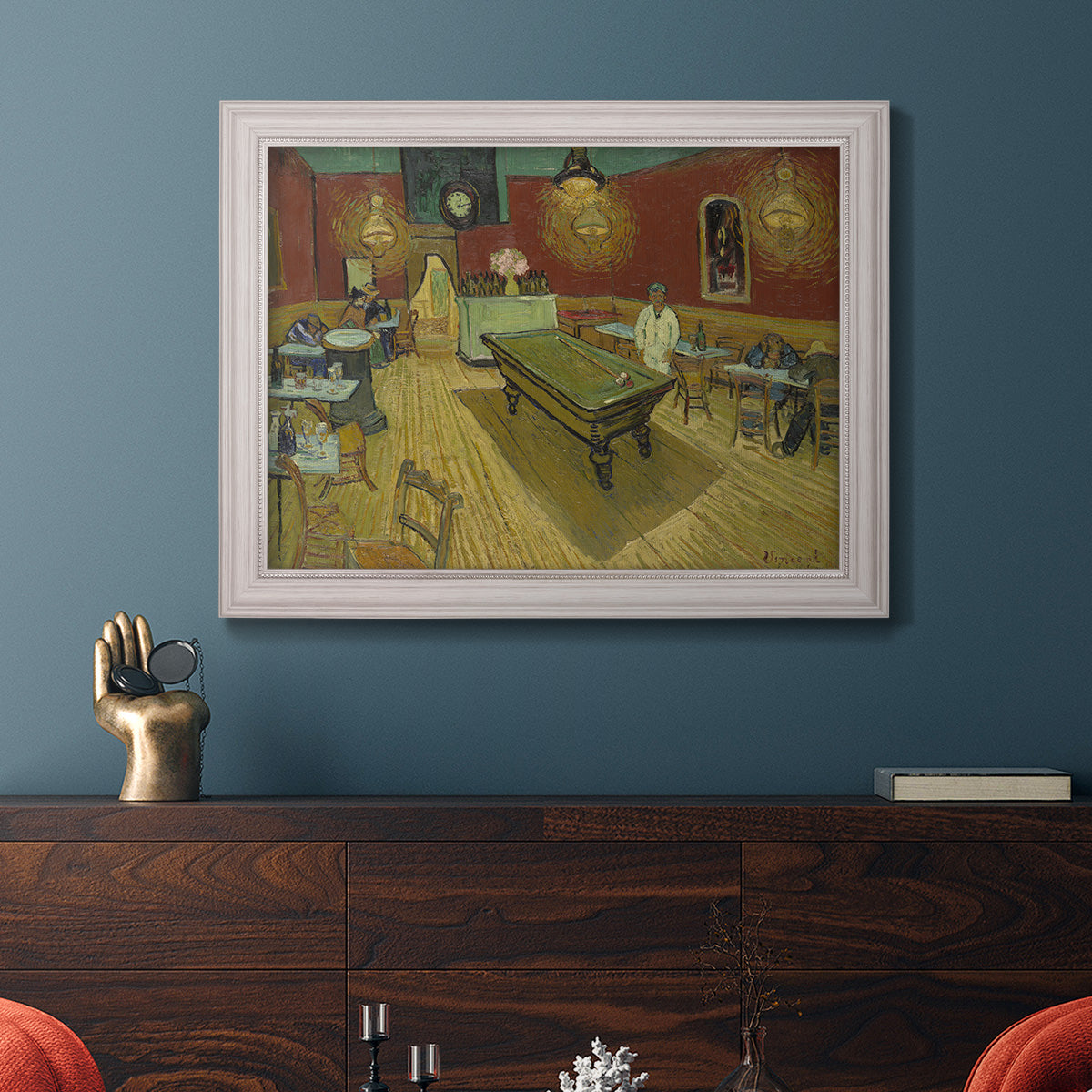 Impressionist interior of a night café by Vincent van Gogh in an ornate weathered white frame displayed in a dark-toned interior setting.