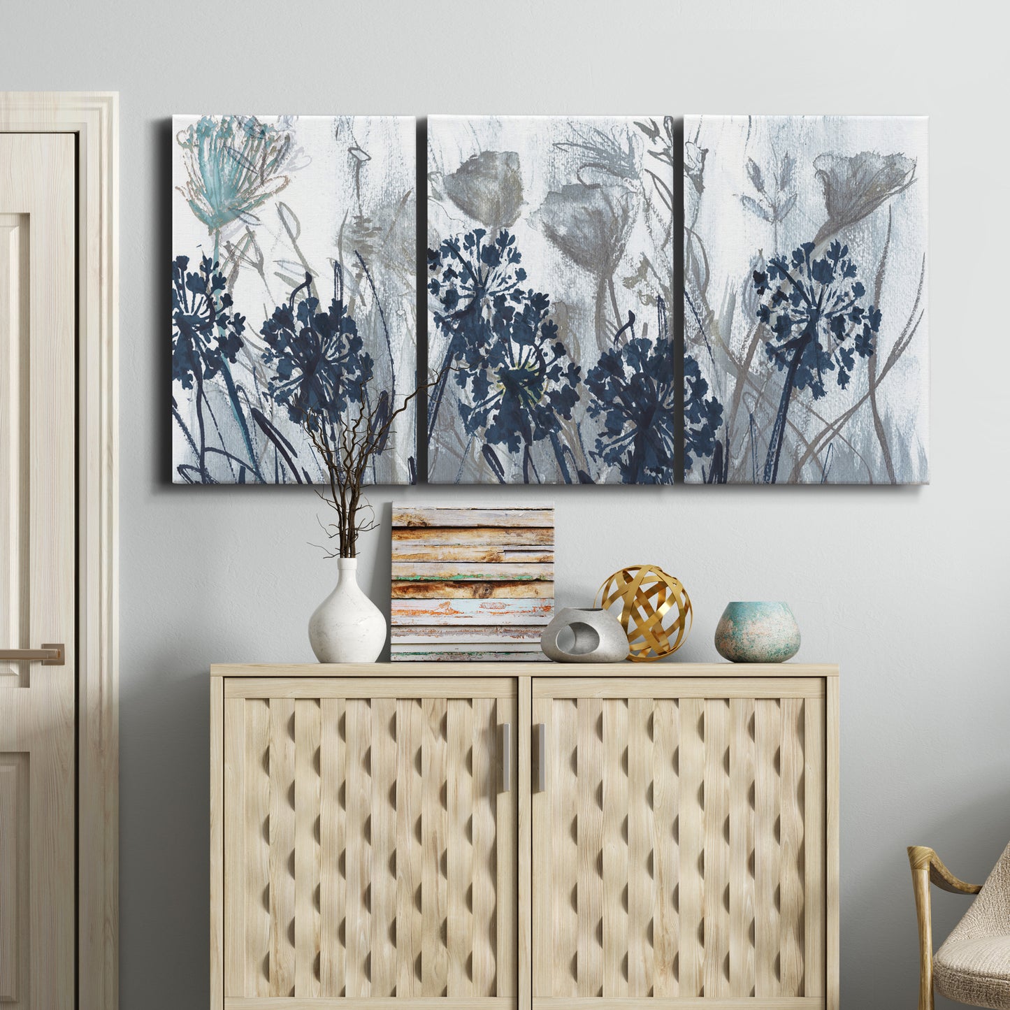 Three-panel canvas wall art featuring indigo floral abstraction, displayed above a cabinet in an entryway.