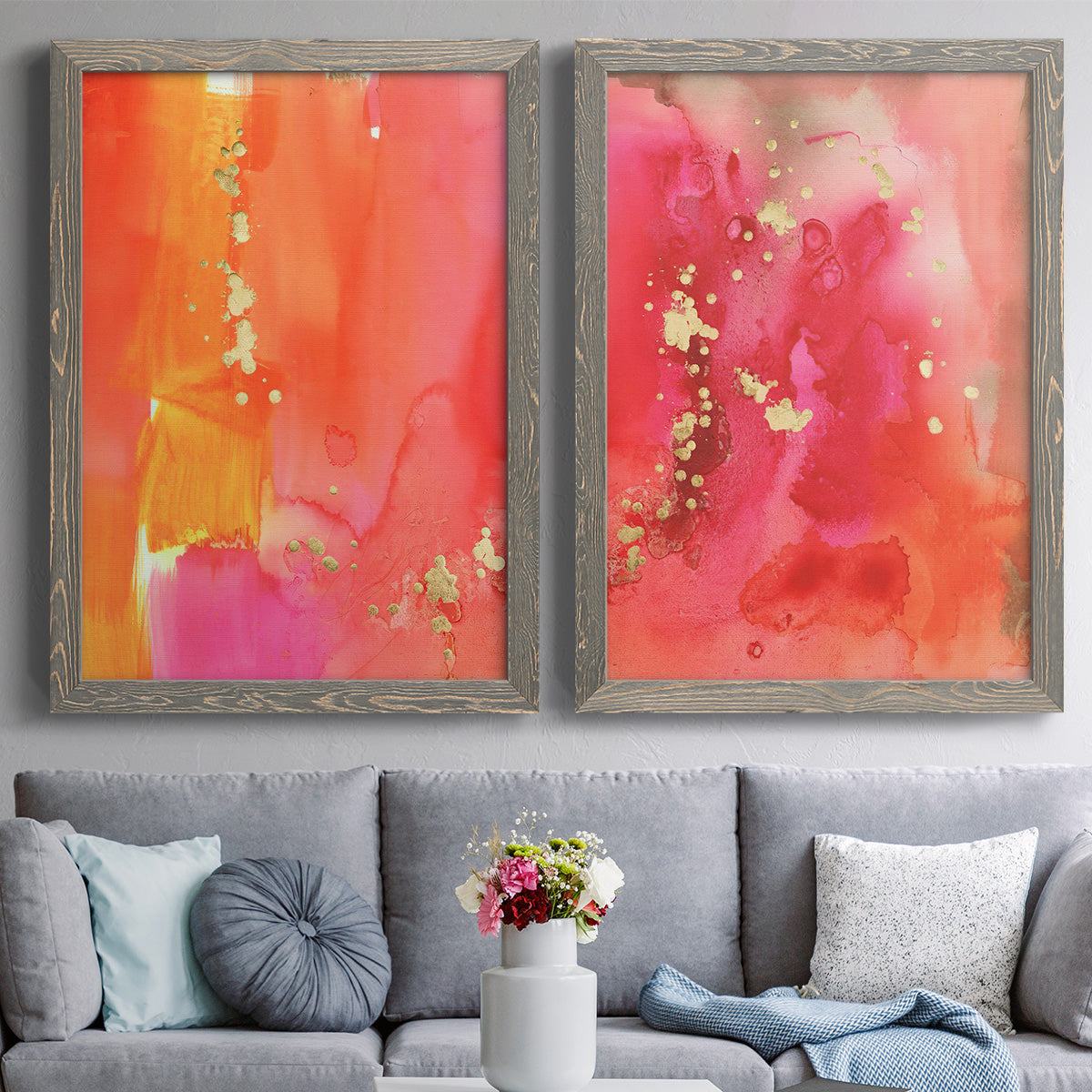 Set of two gray barnwood framed canvas prints depicting paired glamorous fluid abstracts with translucent warm washes, drips, and scattered metallic accents above a sofa in a contemporary living room.