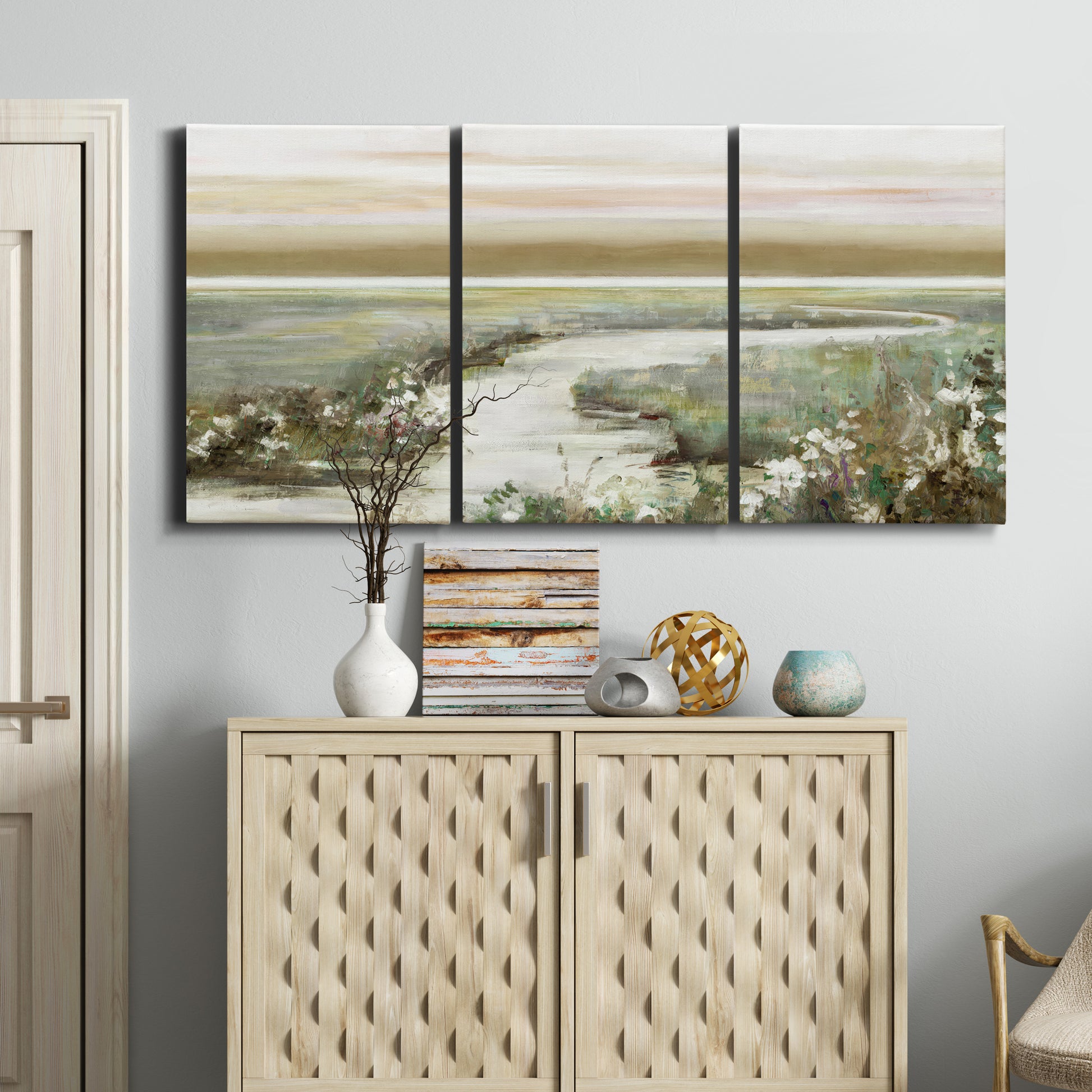 Three-panel canvas wall art featuring pastoral fields under soft sunrise, displayed above a cabinet in an entryway.