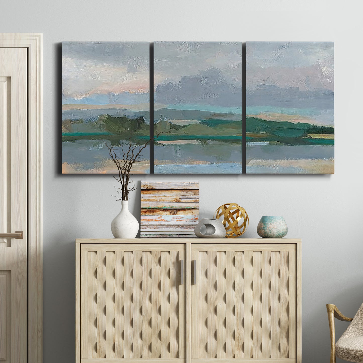 Three-panel canvas wall art featuring twilight landscape with fading light, displayed above a cabinet in an entryway.