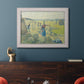 Impressionist rural hay harvest landscape by Camille Pissarro in an ornate weathered white frame displayed in a dark-toned interior setting.