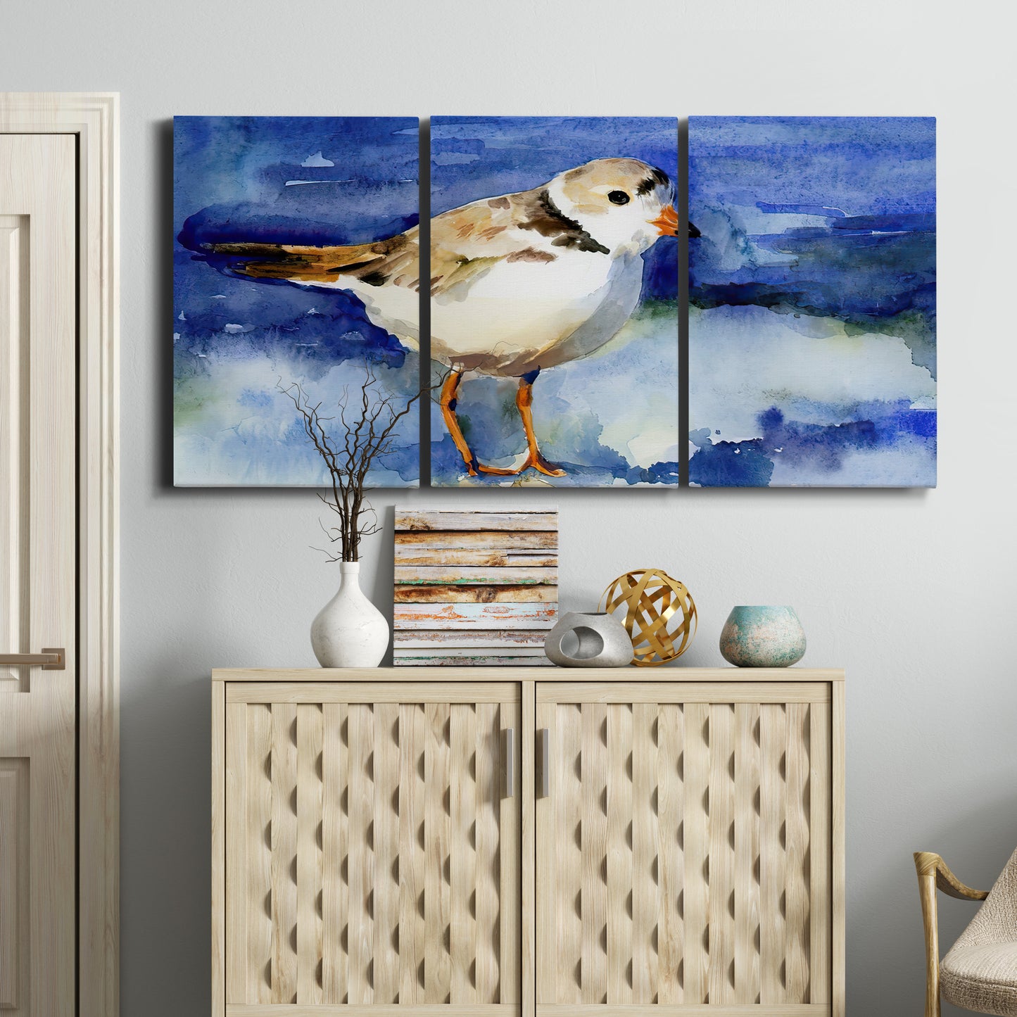 Three-panel canvas wall art featuring shorebirds standing in shallow water, displayed above a cabinet in an entryway.