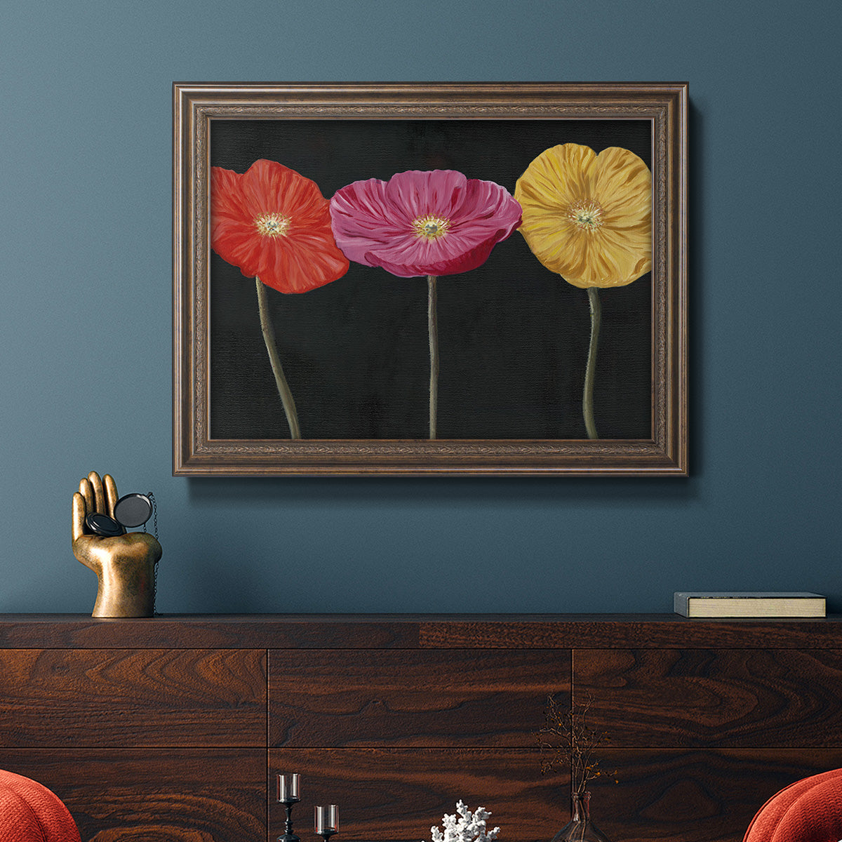 Contemporary poppy flower artwork in an ornate traditional bronze frame displayed in a dark-toned interior setting.