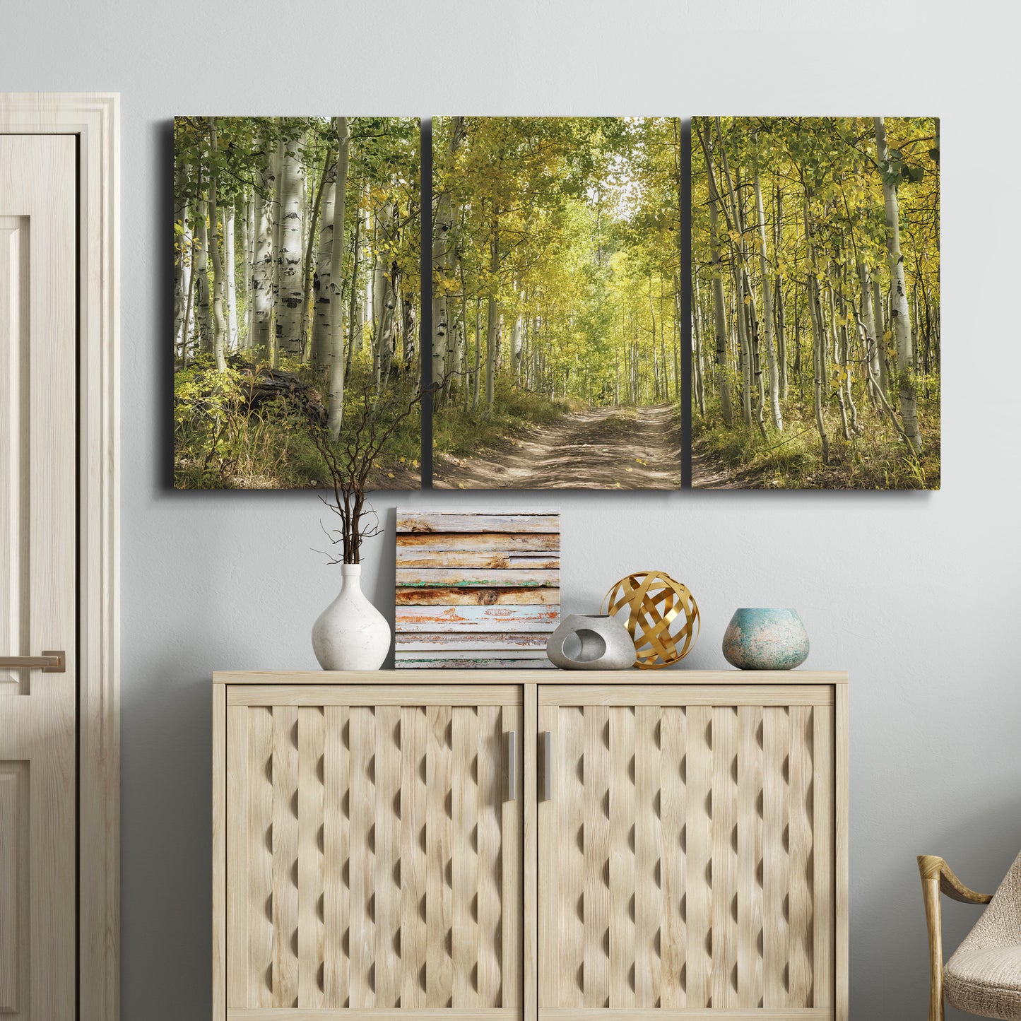 Three-panel canvas wall art featuring tree lined forest road photograph, displayed above a cabinet in an entryway.