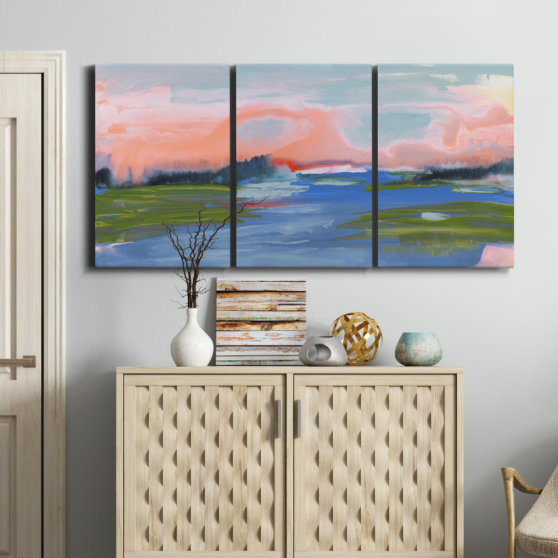 Three-panel canvas wall art featuring sunset reflections across calm sea, displayed above a cabinet in an entryway.