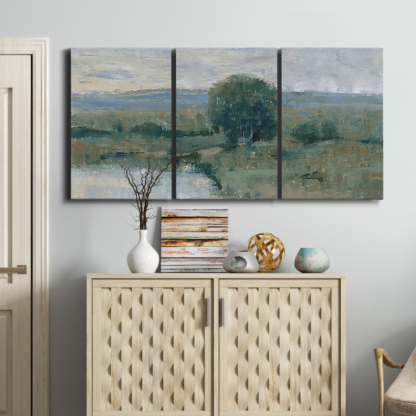 Three-panel canvas wall art featuring riverbank landscape with reflections, displayed above a cabinet in an entryway.