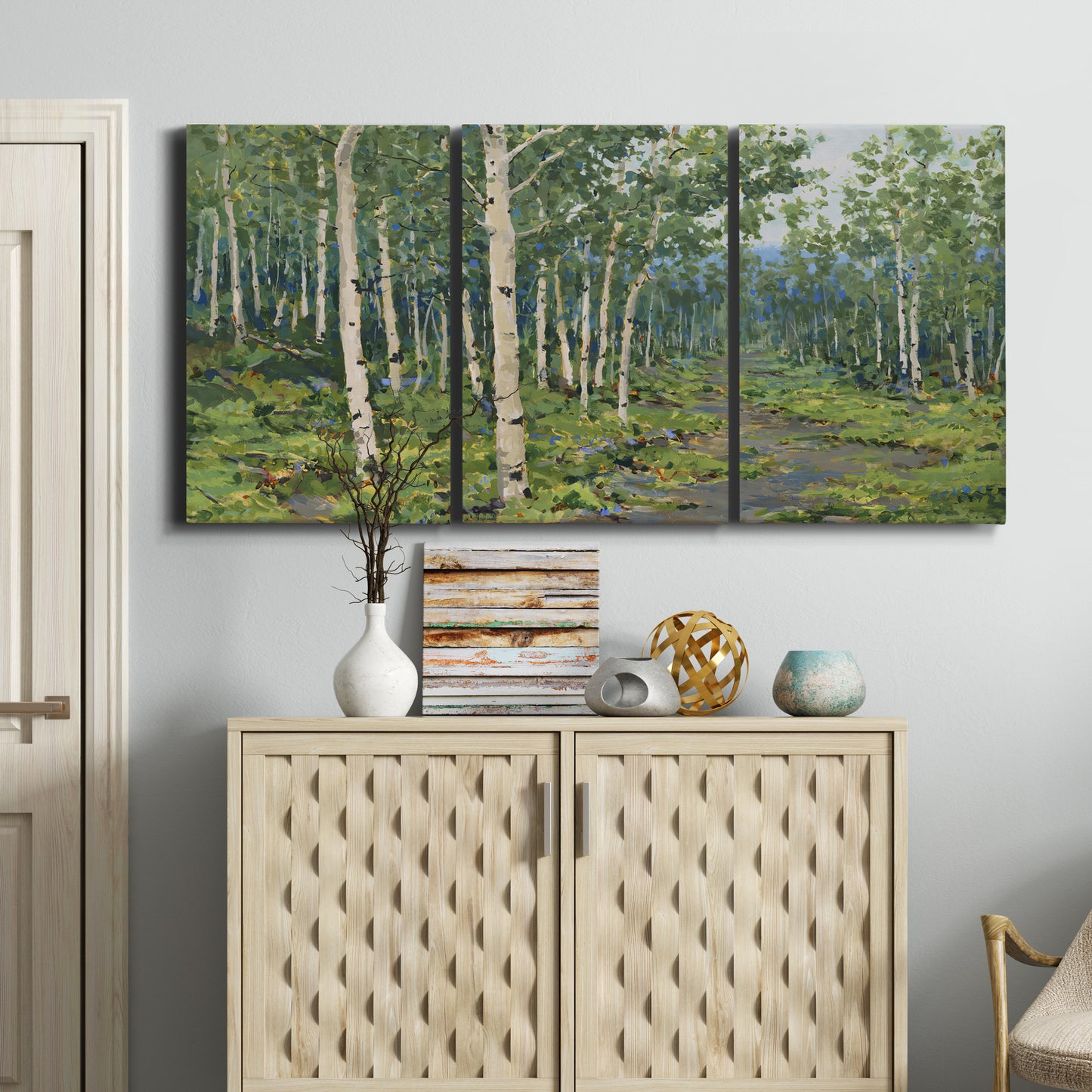 Three-panel canvas wall art featuring woodland forest scene with tall trees, displayed above a cabinet in an entryway.