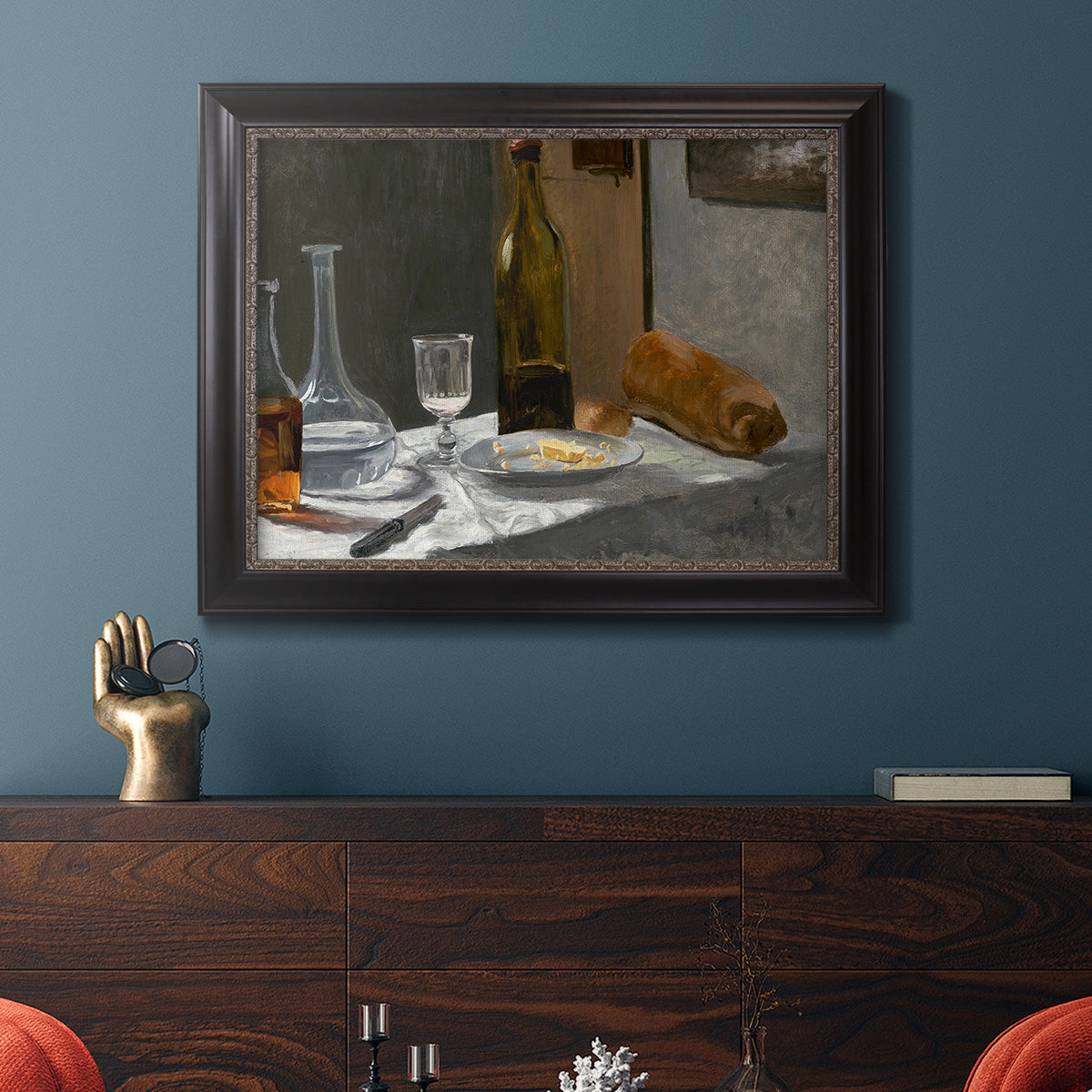 Impressionist still life with wine and bread by Claude Monet in an ornate black frame with gilded inner detail displayed in a dark-toned interior setting.