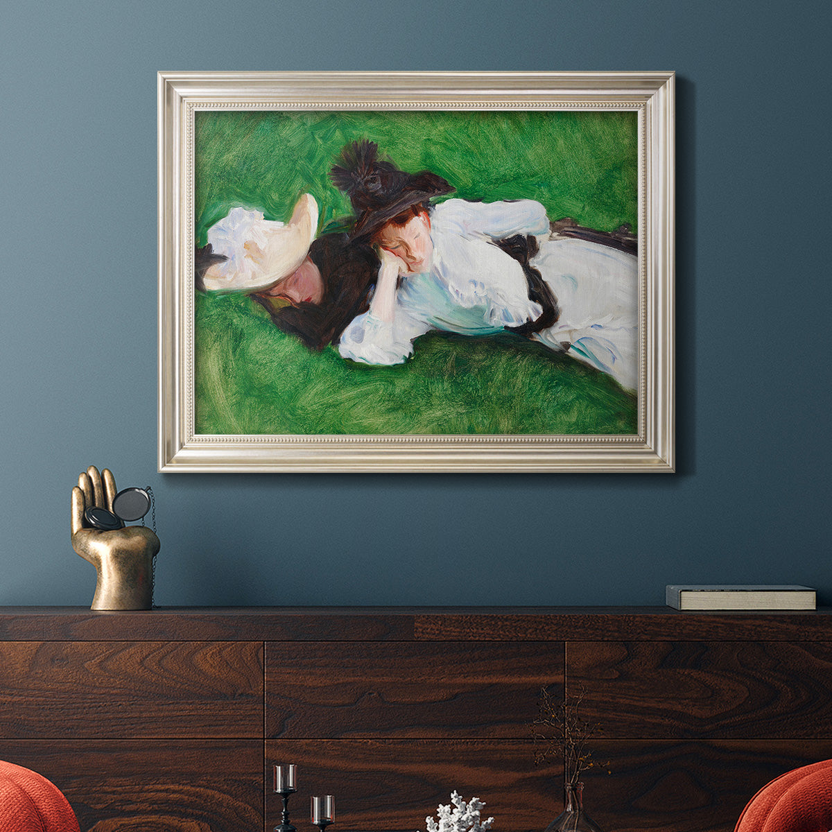 Impressionist outdoor portrait of two girls by John Singer Sargent in an ornate champagne frame displayed in a dark-toned interior setting.