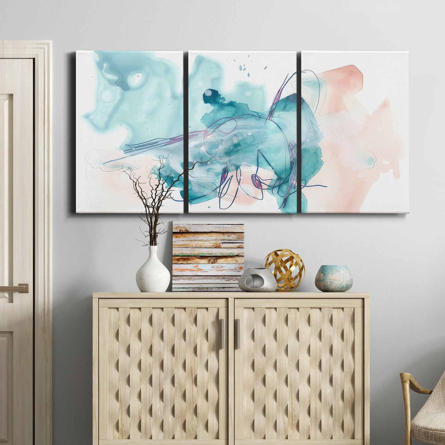 Three-panel canvas wall art featuring soft abstract watercolor forms, displayed above a cabinet in an entryway.