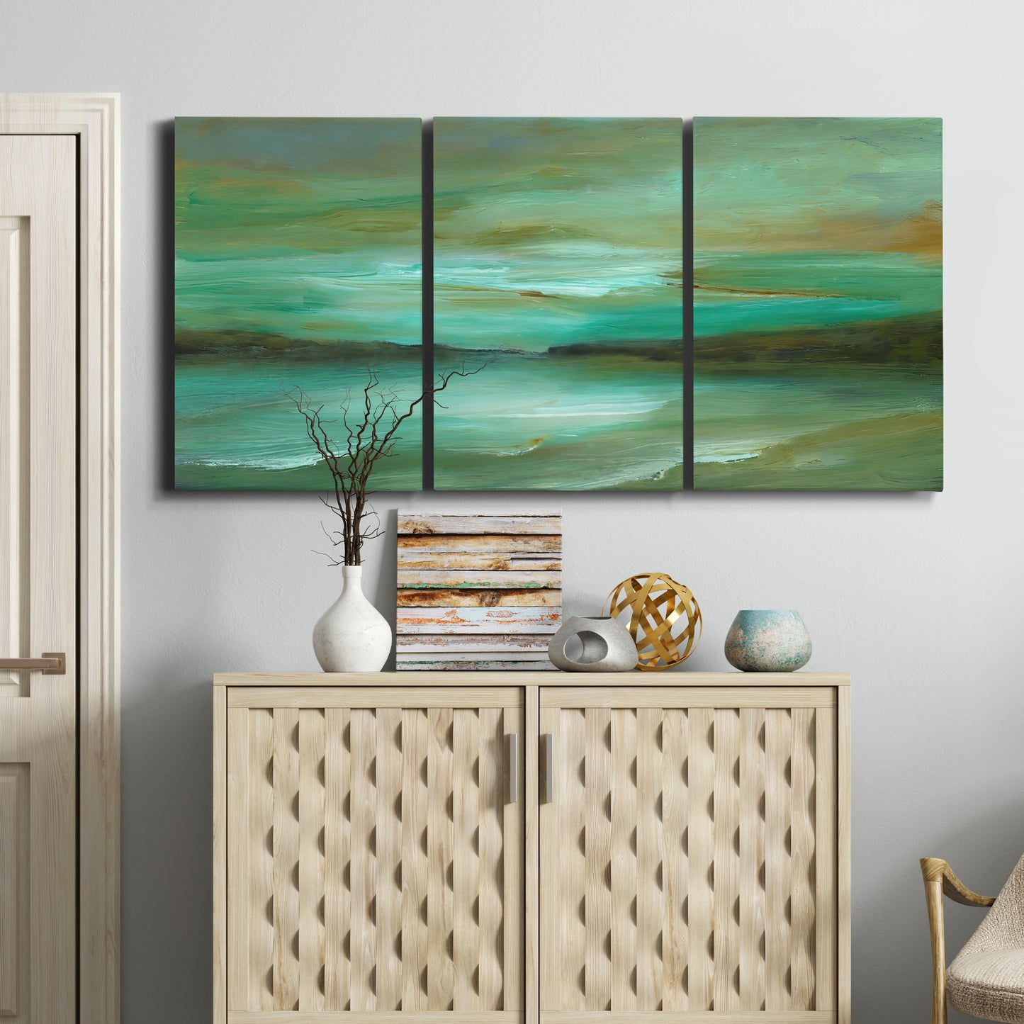 Three-panel canvas wall art featuring hidden coastal cove landscape, displayed above a cabinet in an entryway.