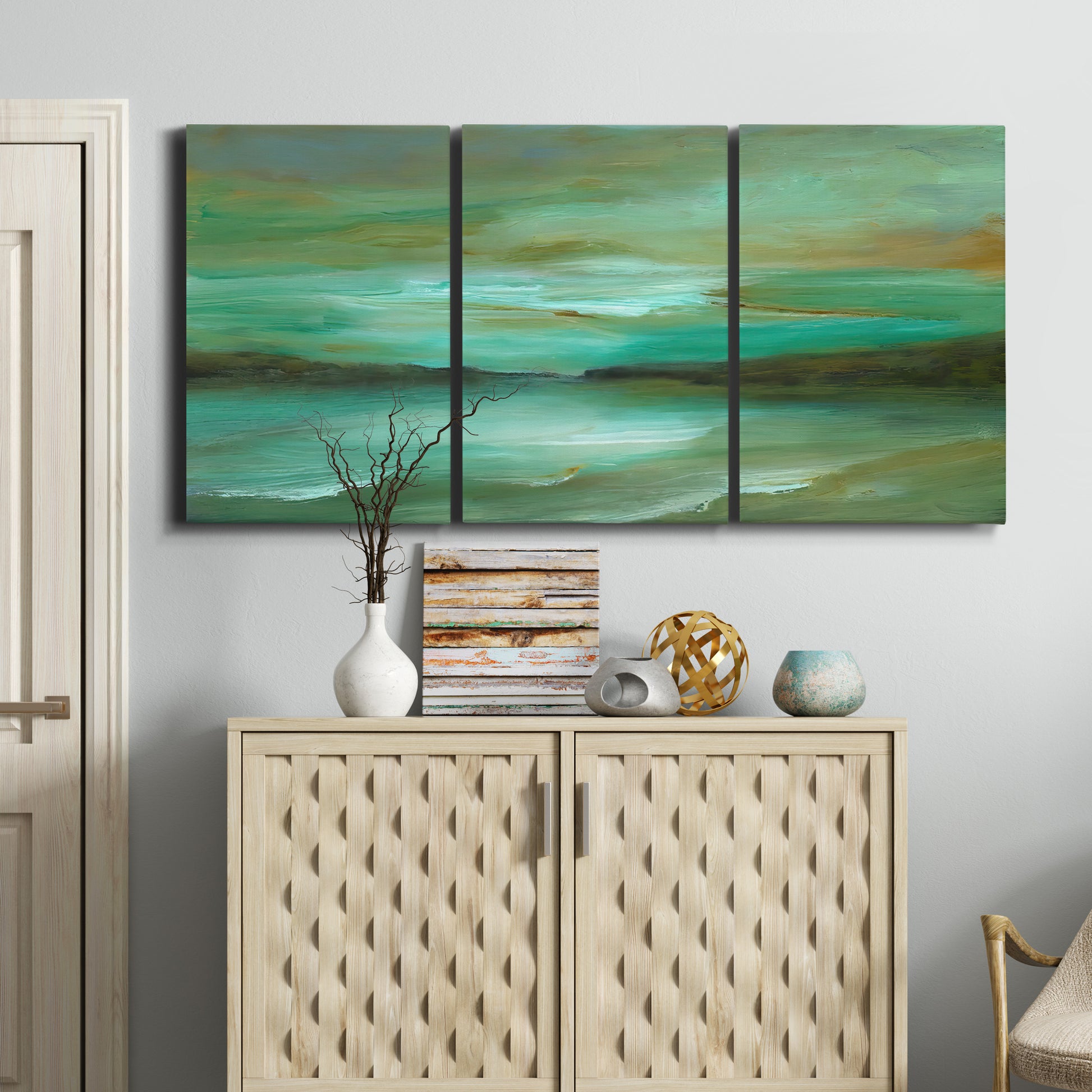 Three-panel canvas wall art featuring hidden coastal cove landscape, displayed above a cabinet in an entryway.