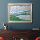 Impressionist river landscape at Vétheuil by Claude Monet in an ornate champagne frame displayed in a dark-toned interior setting.