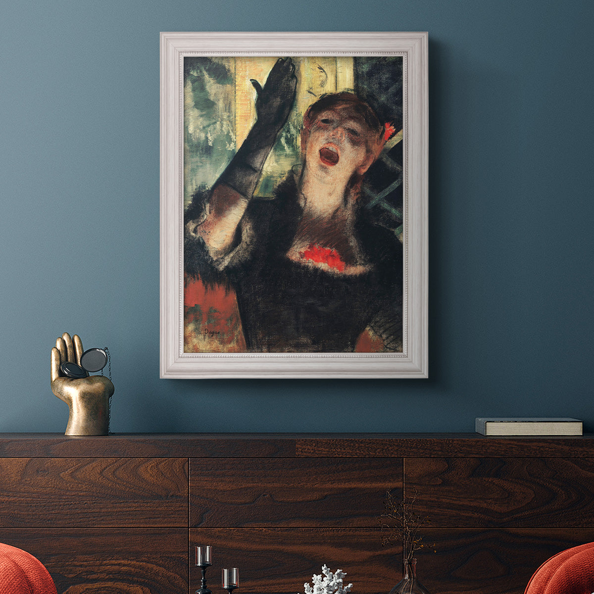 Impressionist portrait of a café singer by Edgar Degas in an ornate weathered white frame displayed in a dark-toned interior setting.